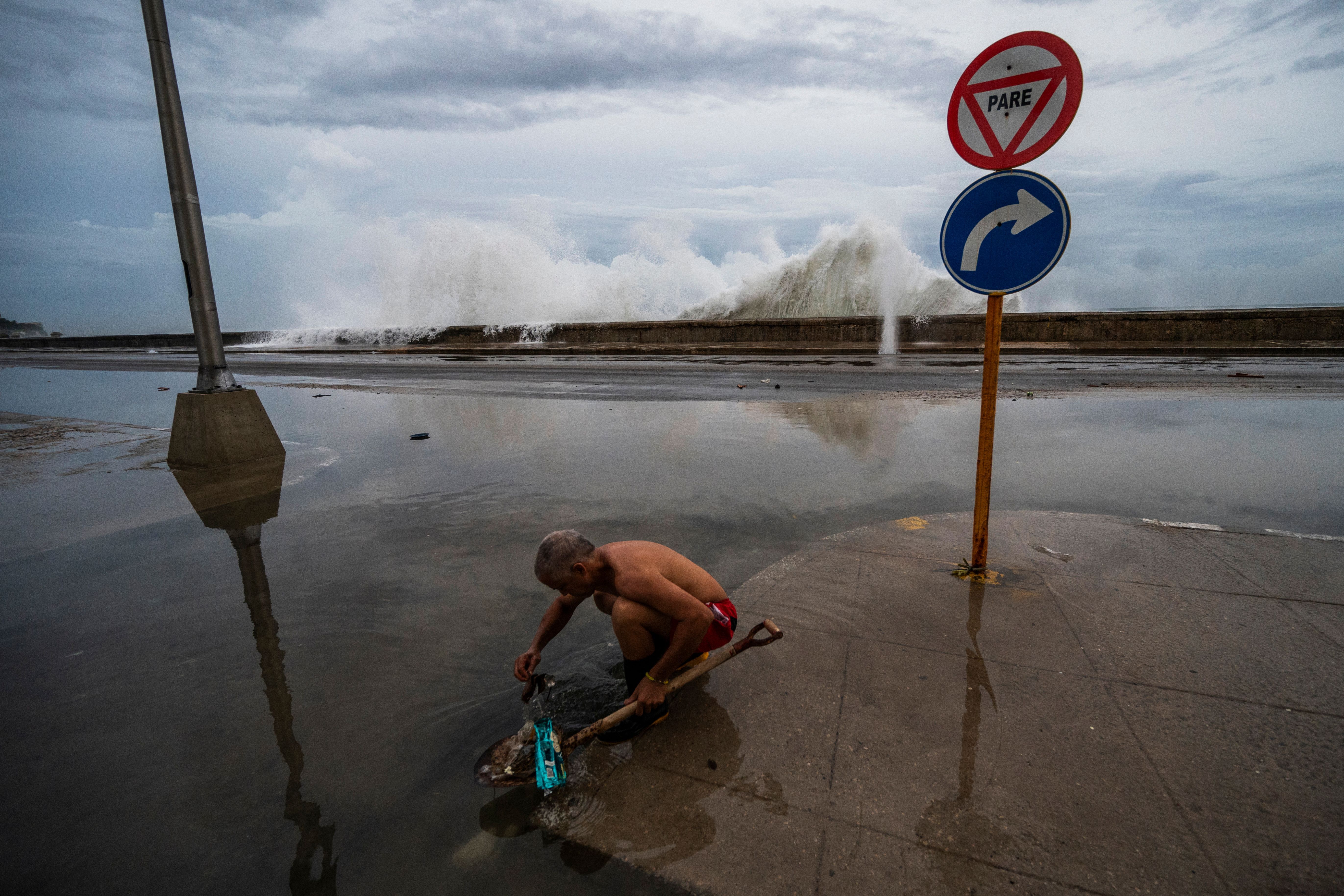 man cleaning sewer in flooded street in Cuba after Hurricane Ian
