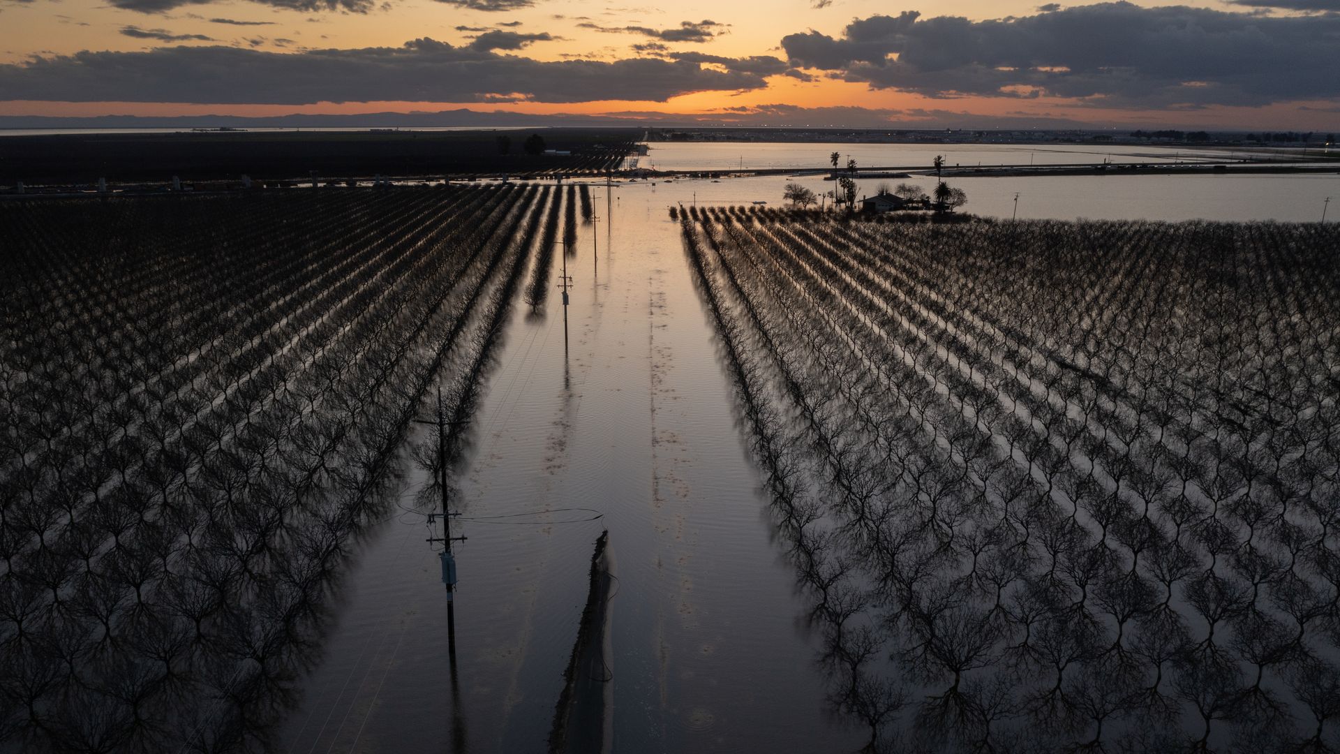 Image of floodwaters in California that are flooding agricultural land at sunset.