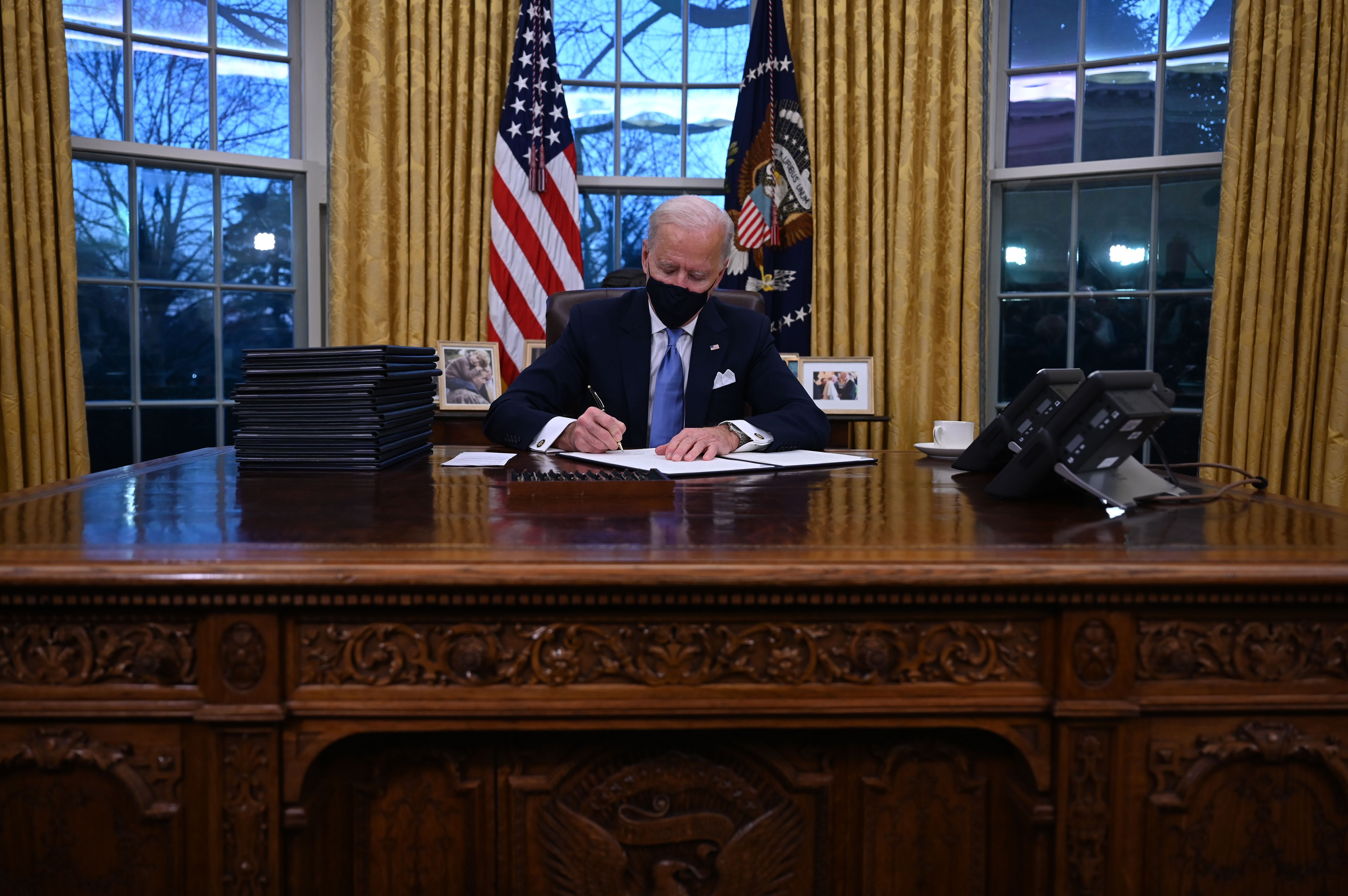 Photo of Joe Biden signing an executive order in the Oval Office