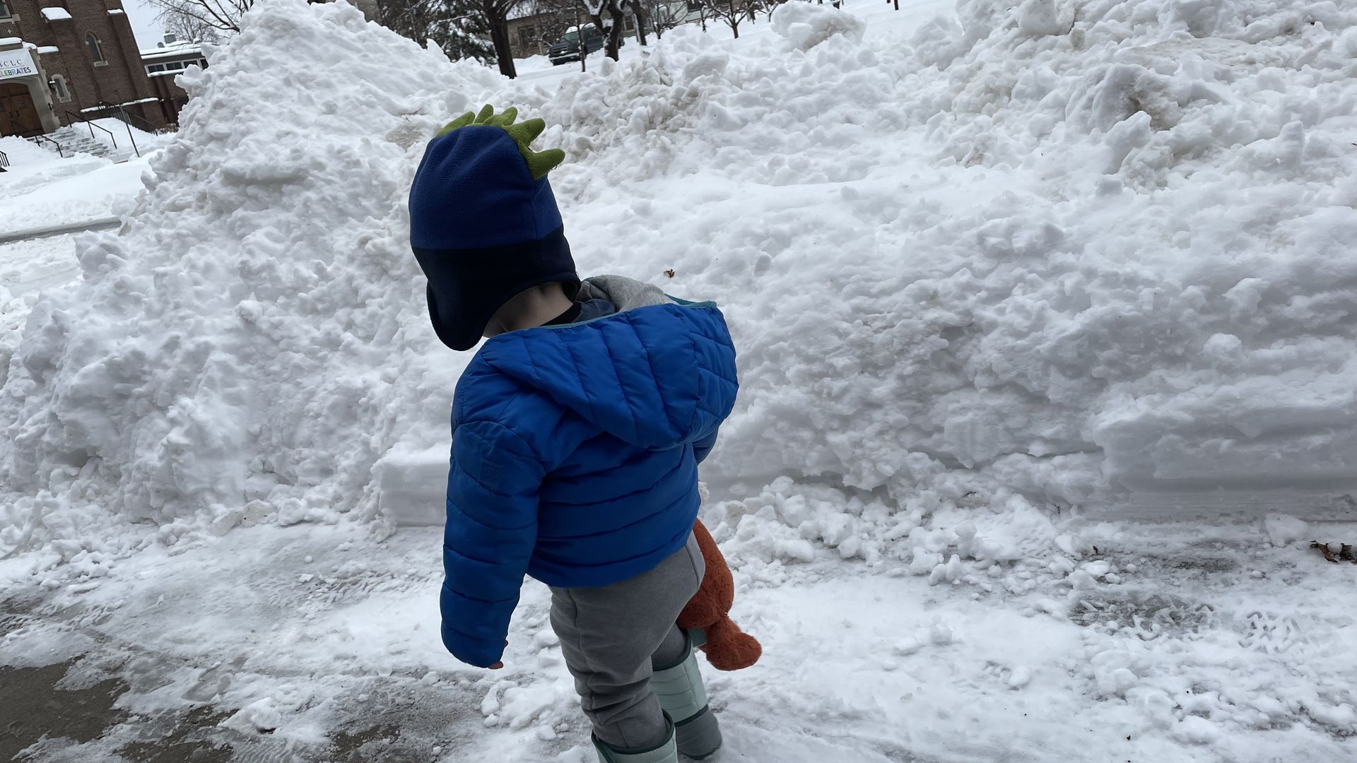 snow piles next to a toddler