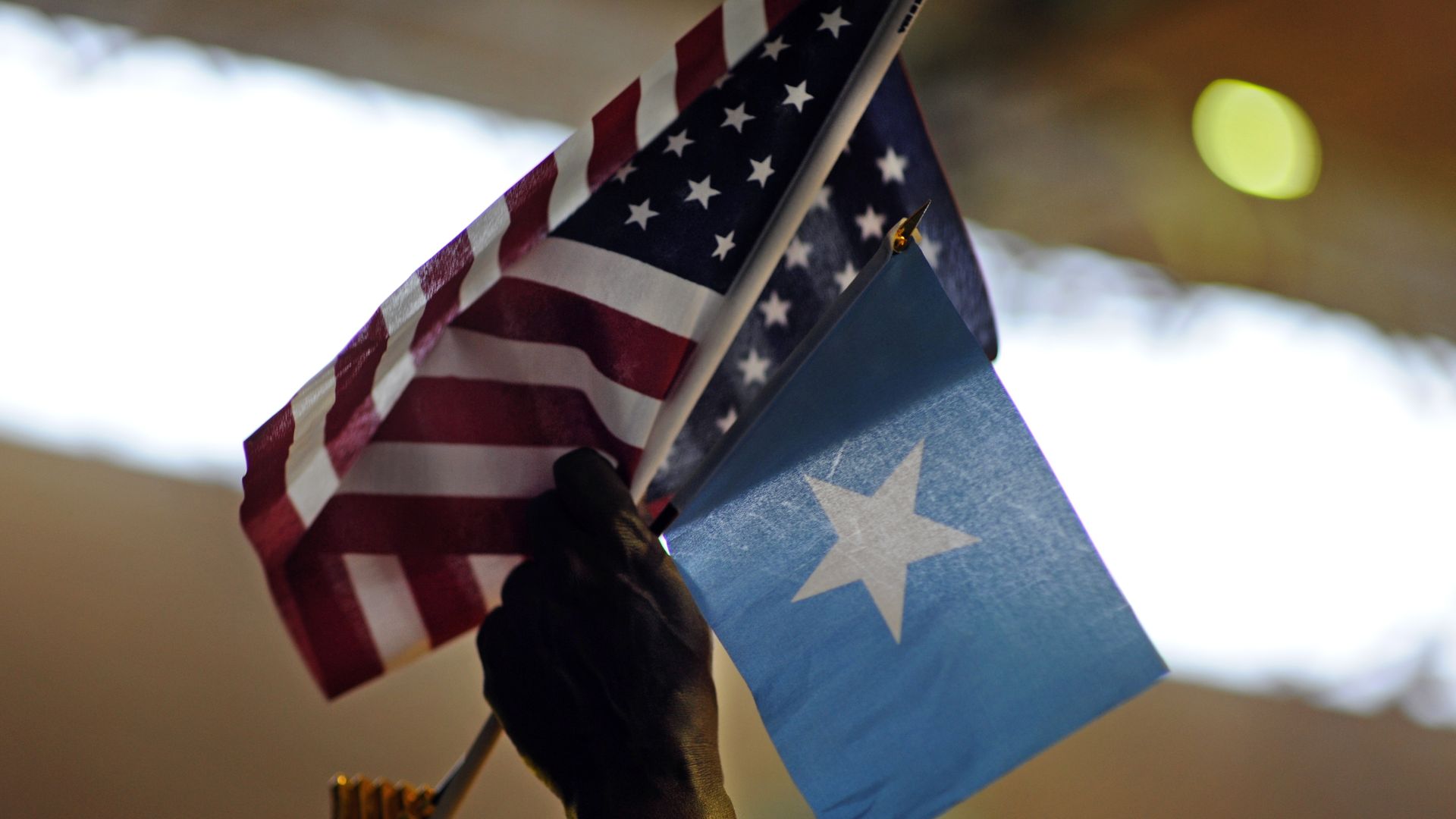 A person holds up Somali and U.S. flags. 