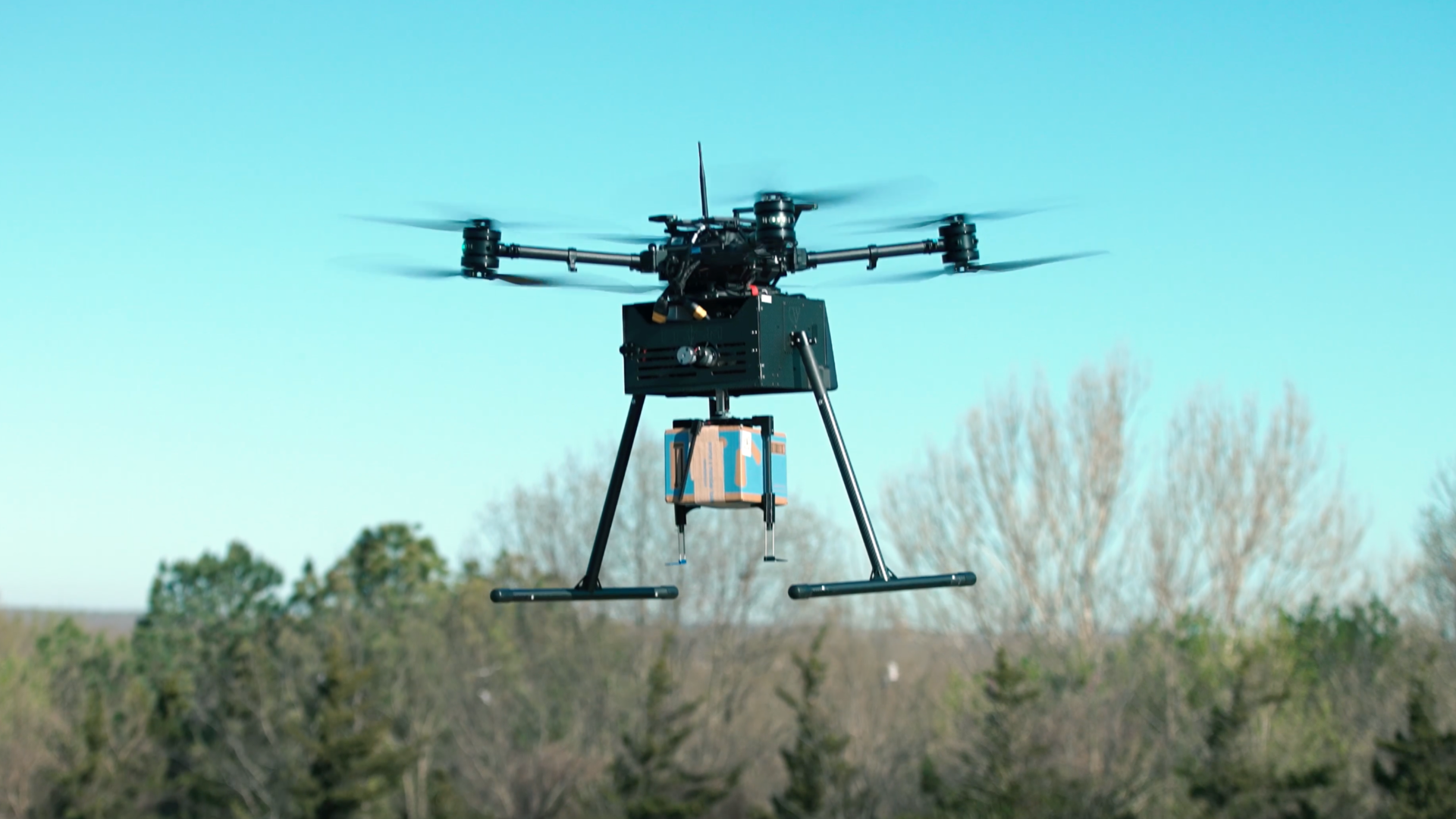 A black drone carrying a Walmart package
