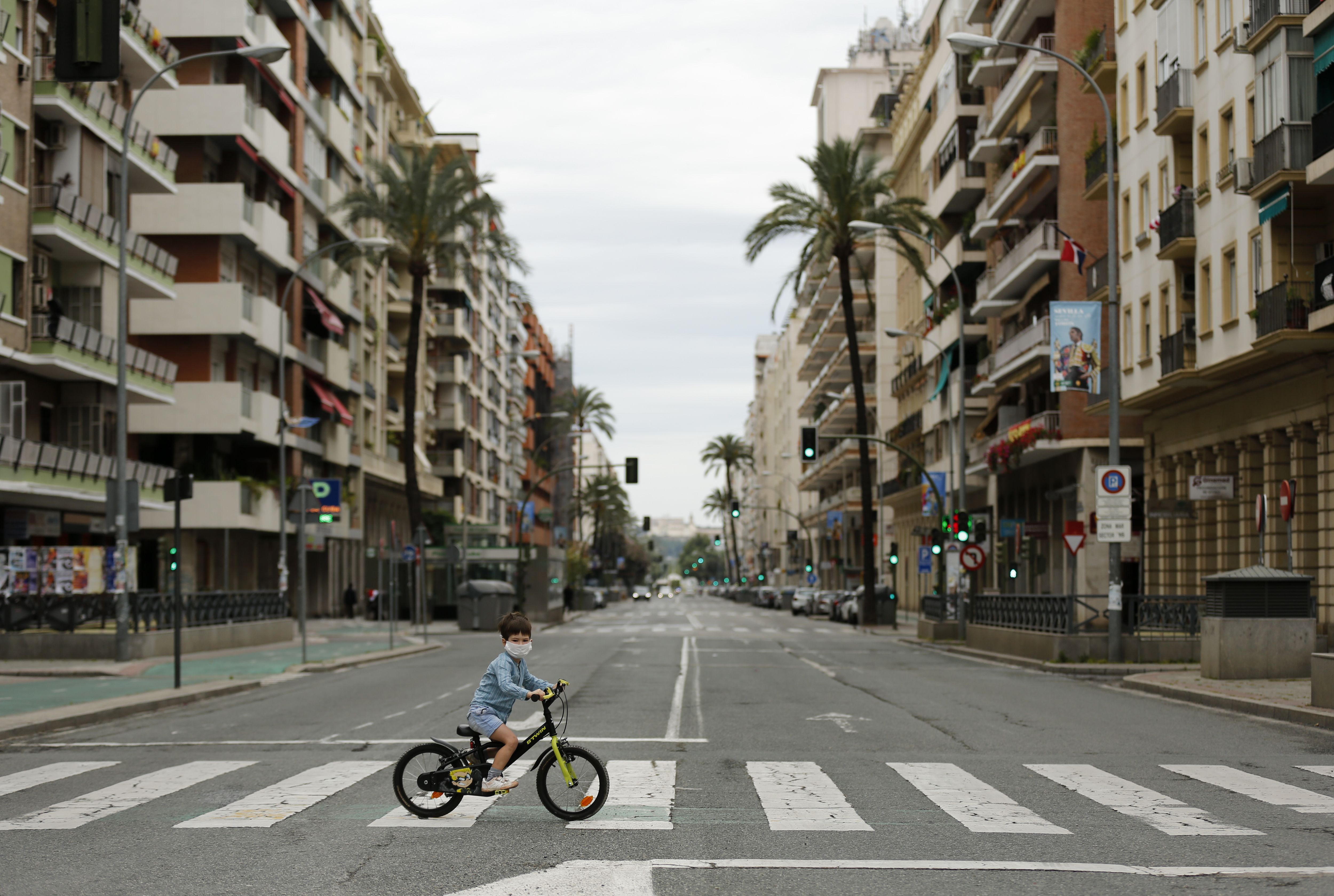 In this image, a boy rides his bicycle across an empty street