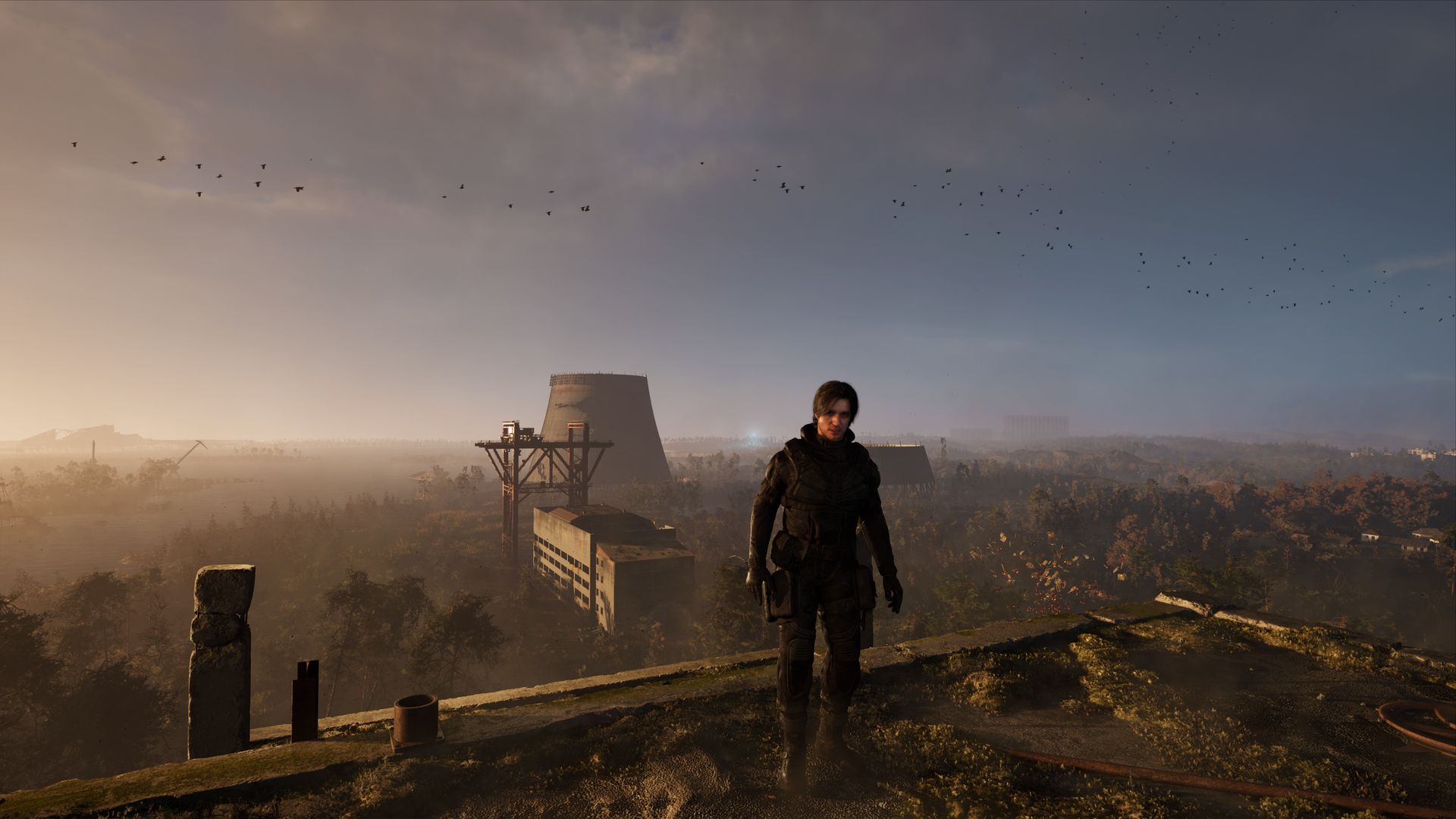 Video game screenshot of a man standing on the outskirts of Chernobyl, with a cooling tower behind him. 