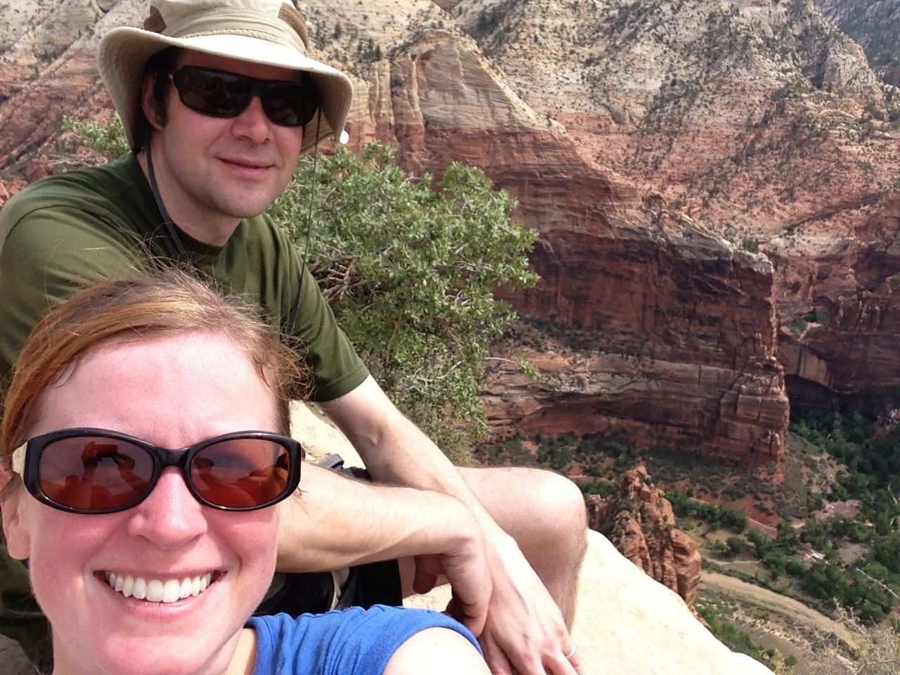 A man and woman in a selfie on a cliff in a red rock canyon.