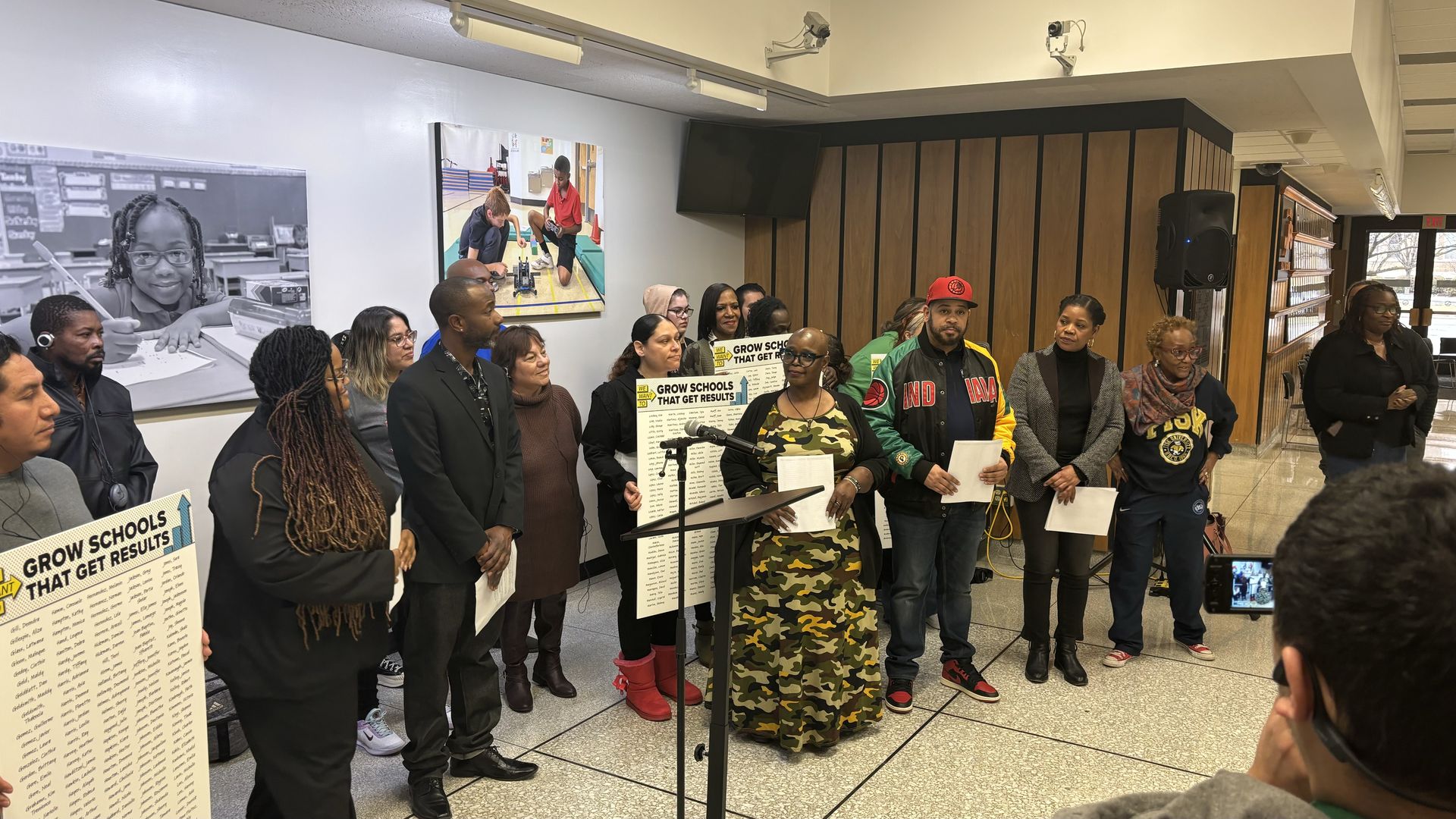 A group of people standing in front of a microphone. Some are holding signs. 