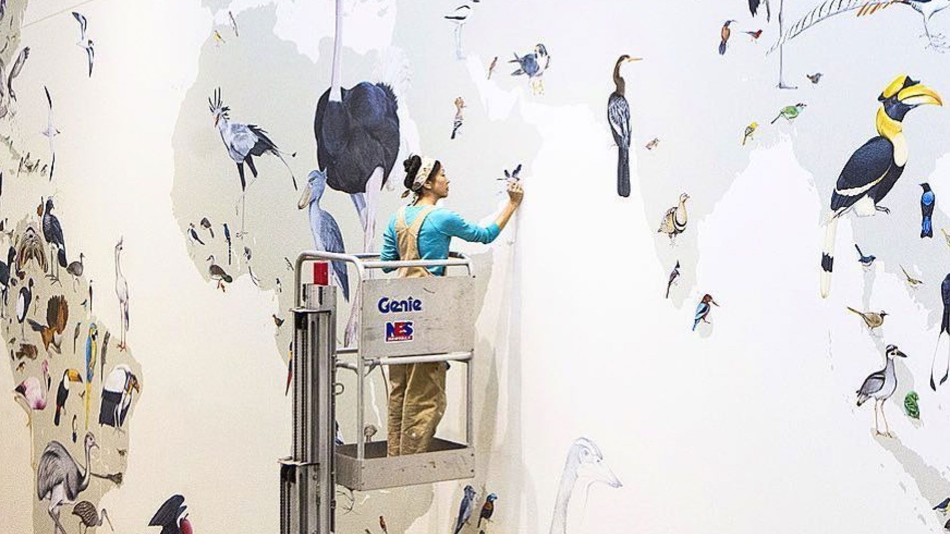 Photo of artist working on bird mural