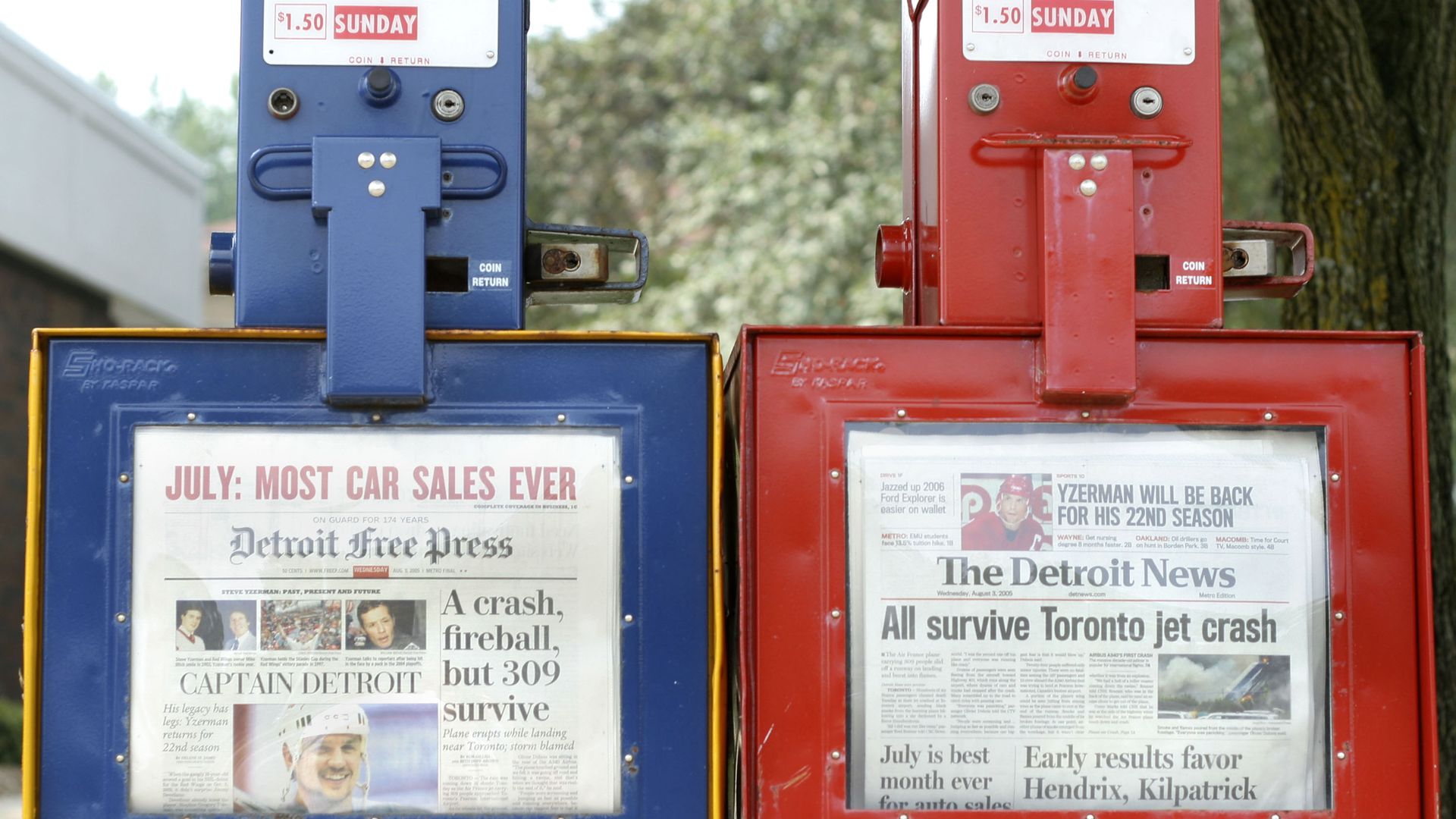 A blue newspaper box holds the Free Press copies and red holds the Detroit News copies 