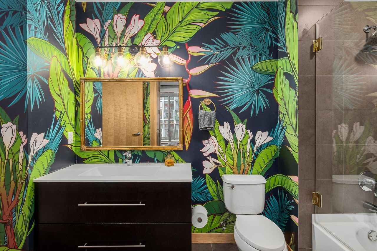 A bathroom with colorful jungle wallpaper.