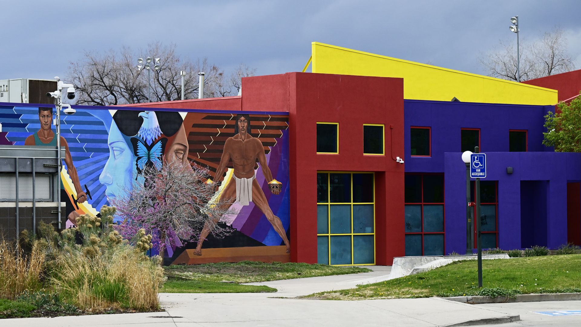 A colorful set of buildings next to a mural depicting indigenous people. 