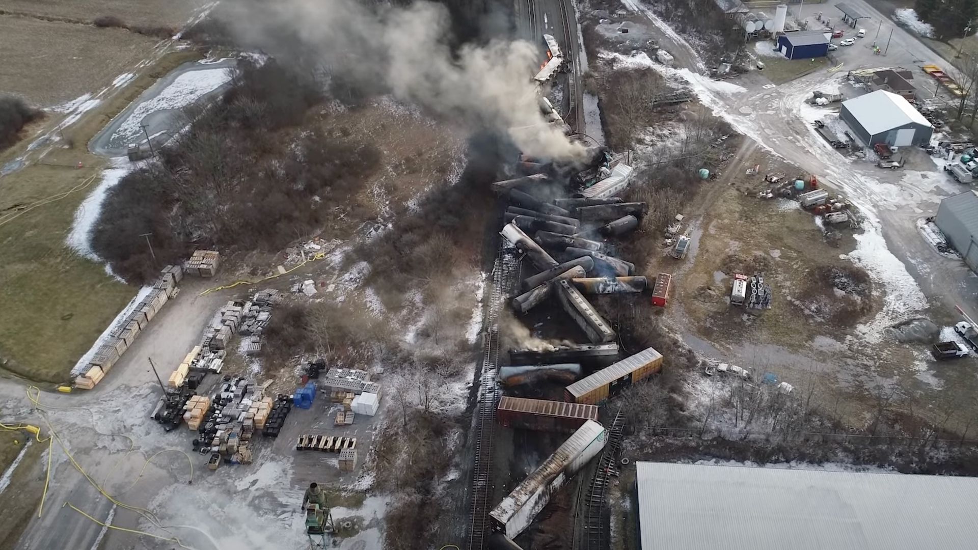 Aerial photo of the site of the derailed freight train, showing smoke billowing from a pile of collapsed train cars
