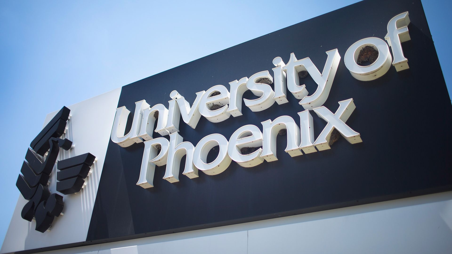 A black sign with white lettering marks the location of the University of Phoenix.