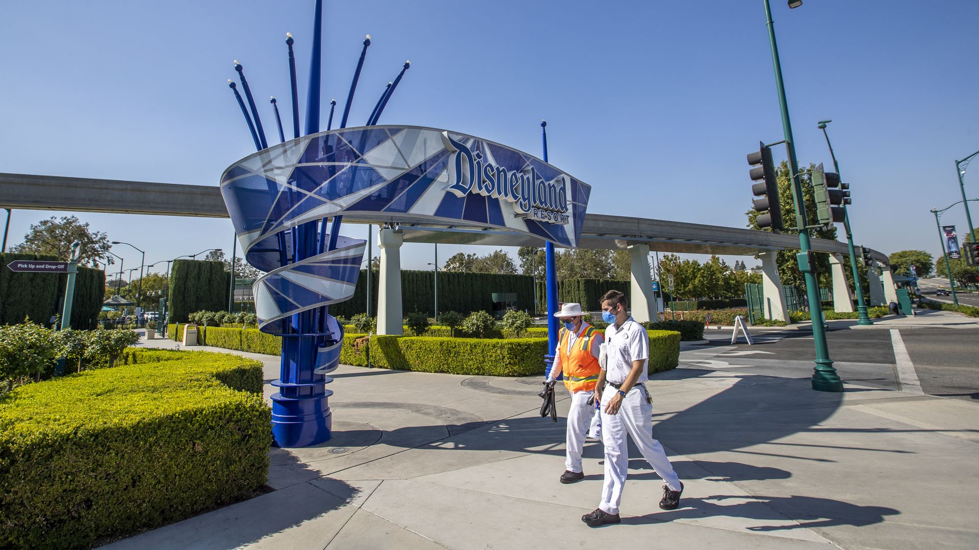 Picture of disney employees walking past the entrance to Disneyland Park