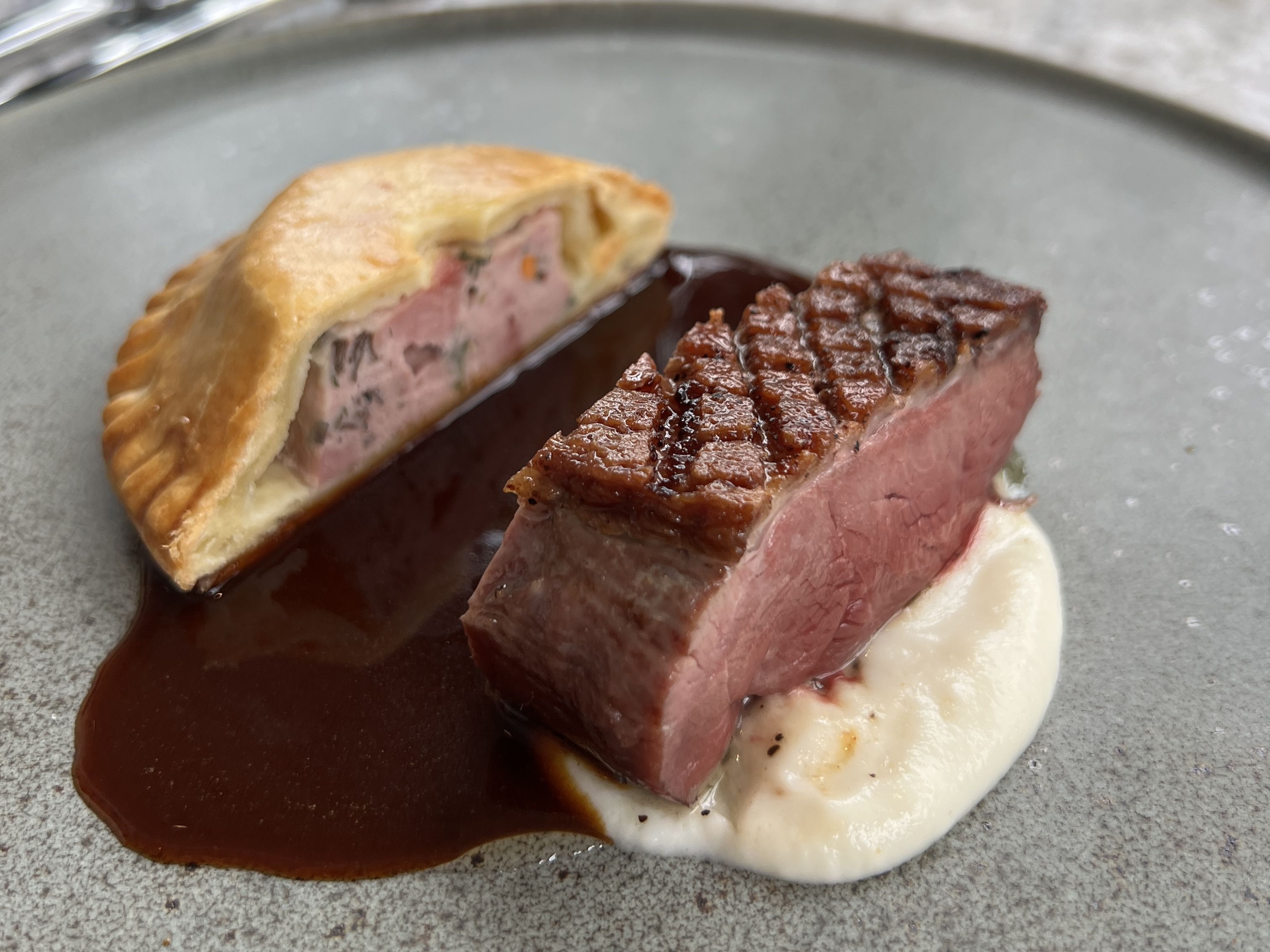 steak and empanada dish with sauce in the center