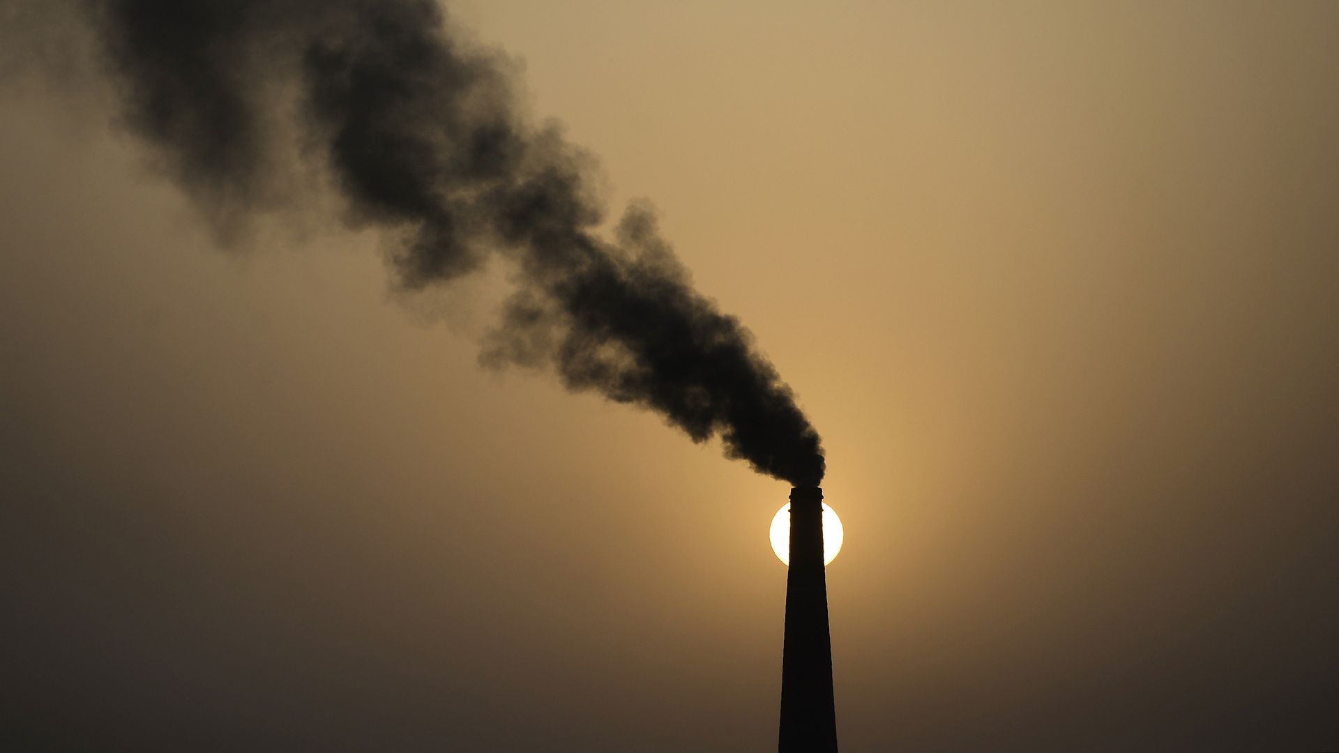 A chimney of a brick factory emits smoke during sunset in Jalandhar on May 31, 2018.