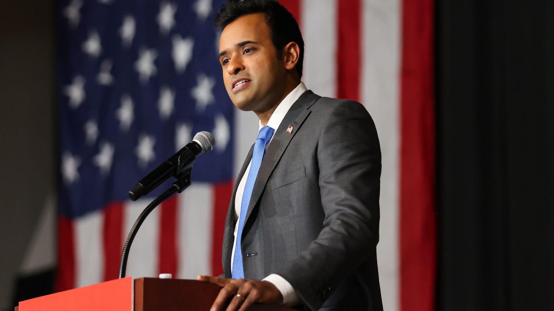 Vivek Ramaswamy speaks into a microphone on a lectern. 