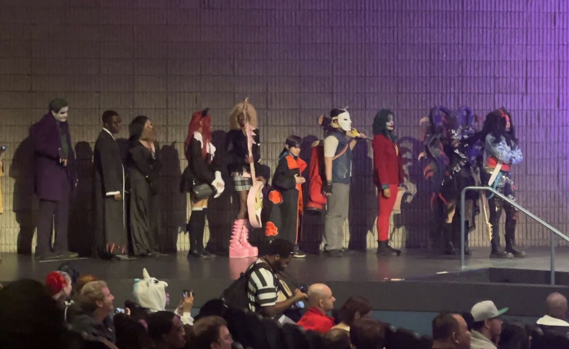 Several people dressed in costumes wait in line for the cosplay contest.