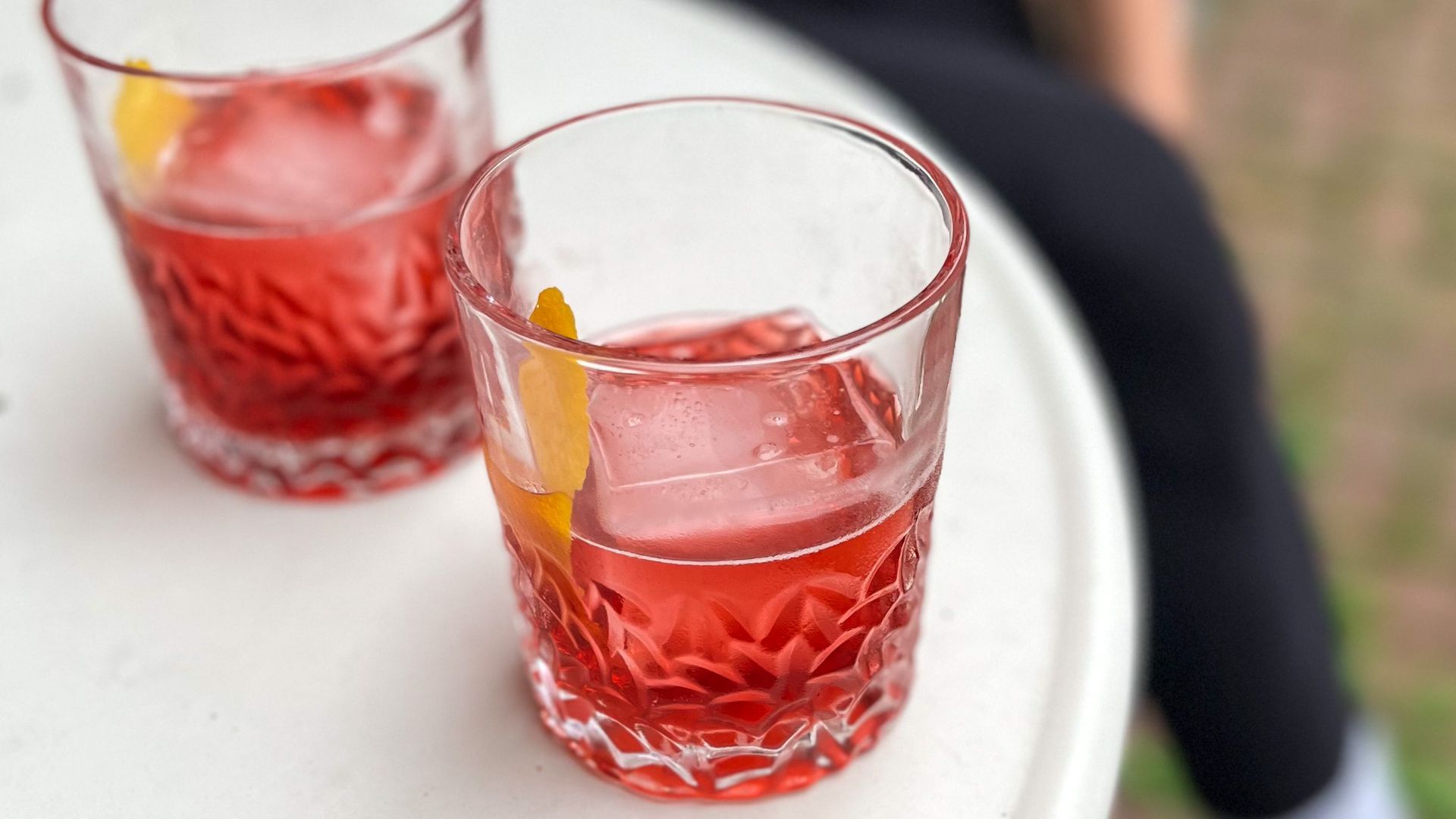 A cocktail made from Dumpster Juice vermouth with a square ice cube and an orange peel.
