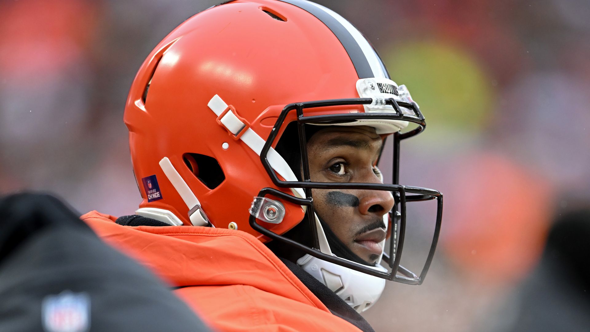 Browns quarterback Deshaun Watson sits on the bench with his helmet on.