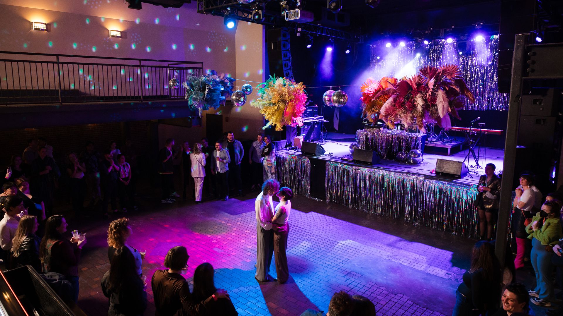 Avery, left, and Sarah, right, have their first dance at The Sinclair's dance floor surrounded by people at the "Queerly Beloved"  wedding party.