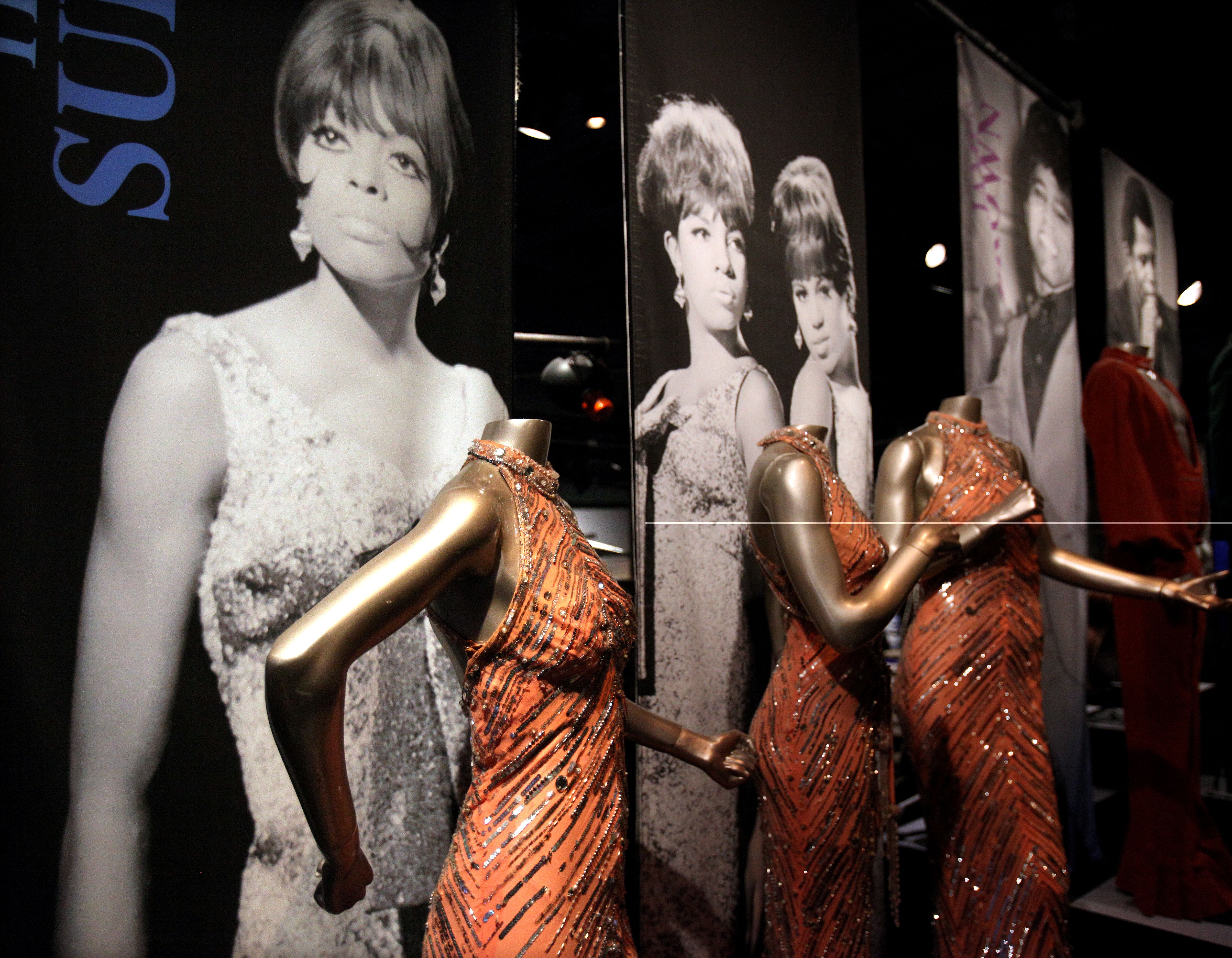 Photo of Diana Ross and the Supremes behind shiny copper dresses on mannequins.