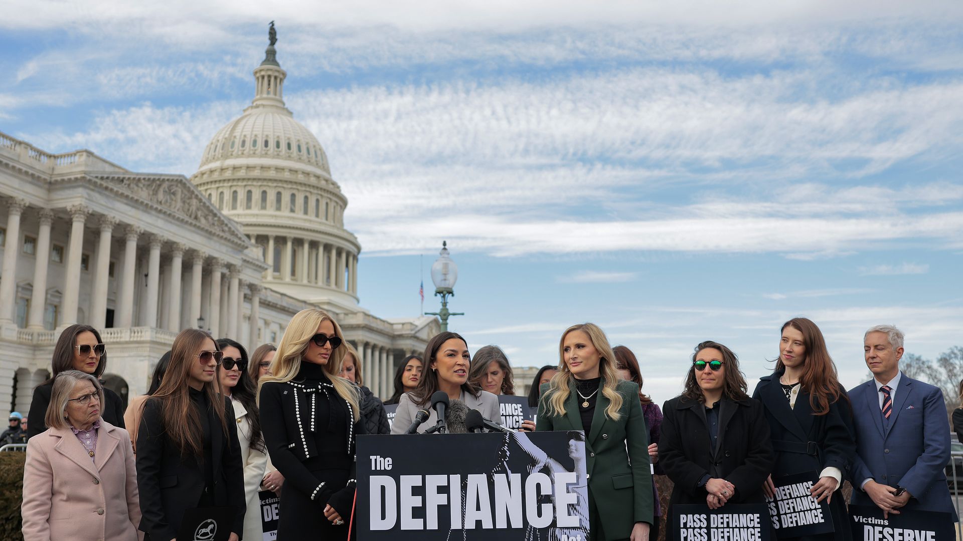 A group of people stand in front of the Capitol building