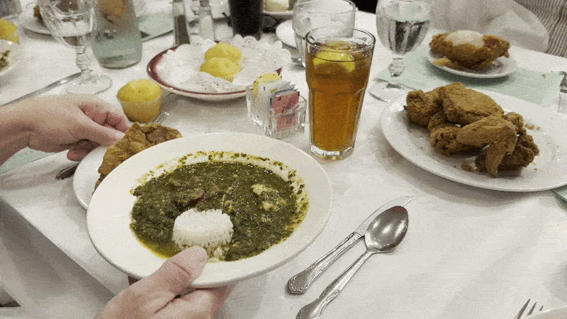Image shows a table with green gumbo and fried chicken.
