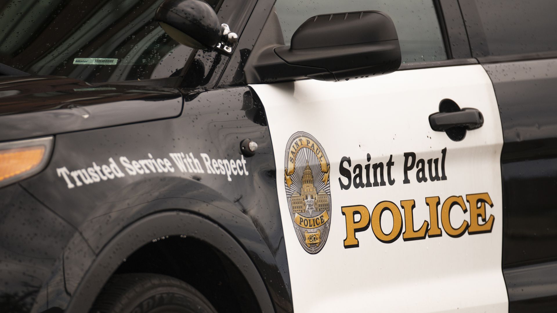 A close-up shot of a black-and-white St. Paul police cruiser bearing the slogan "Trusted Service With Respect"