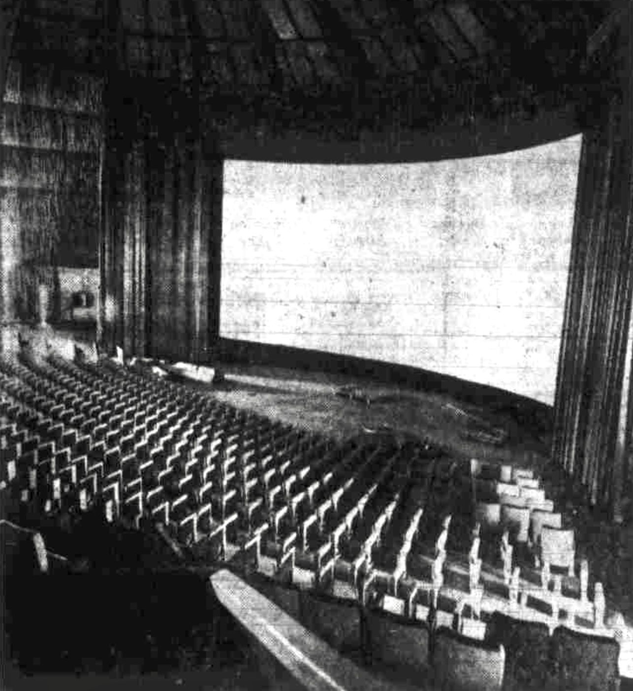 A black and white photo of an empty movie theater in a round building.