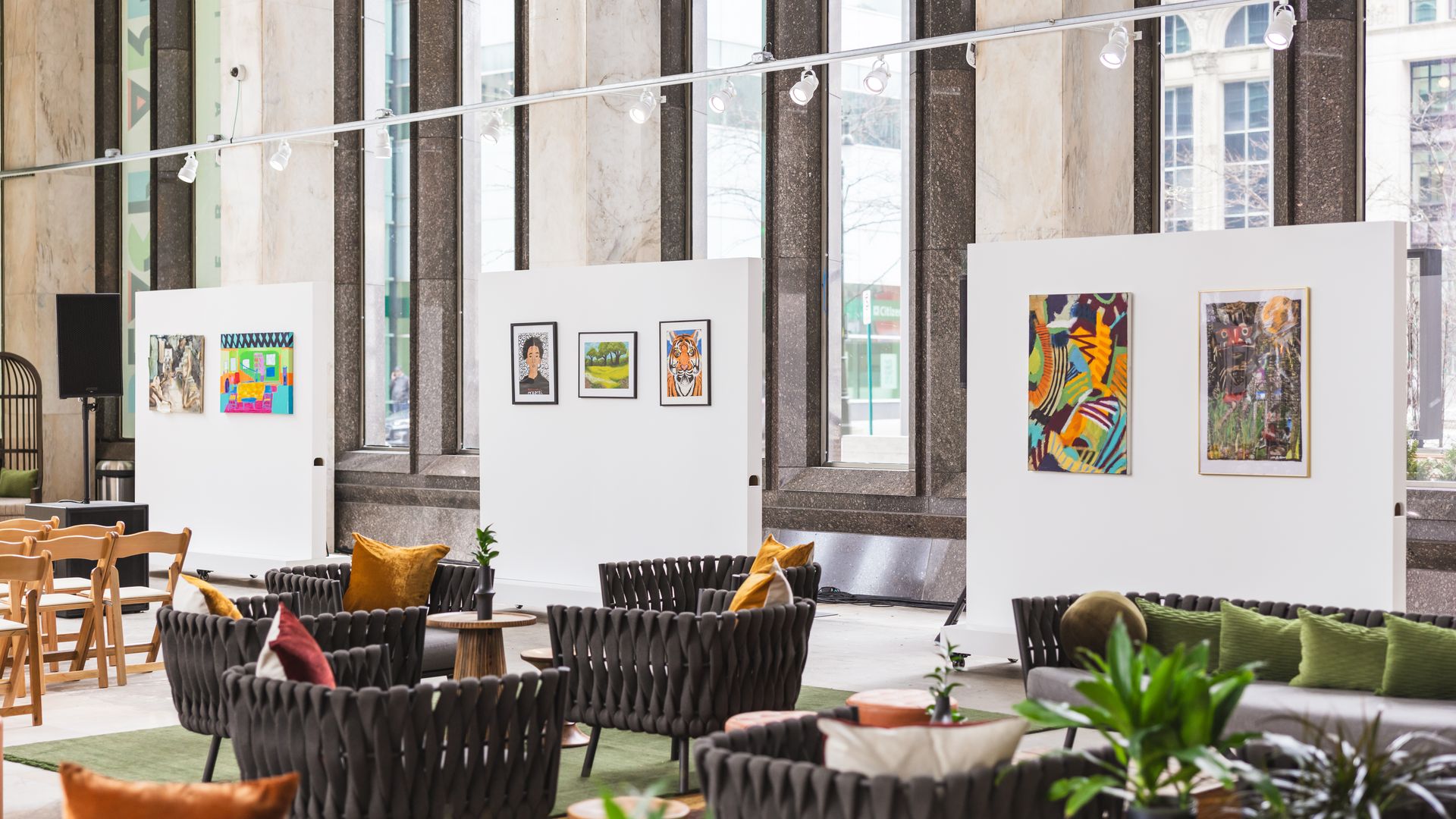 Paintings on walls in a large room with chairs and tables for lounging.