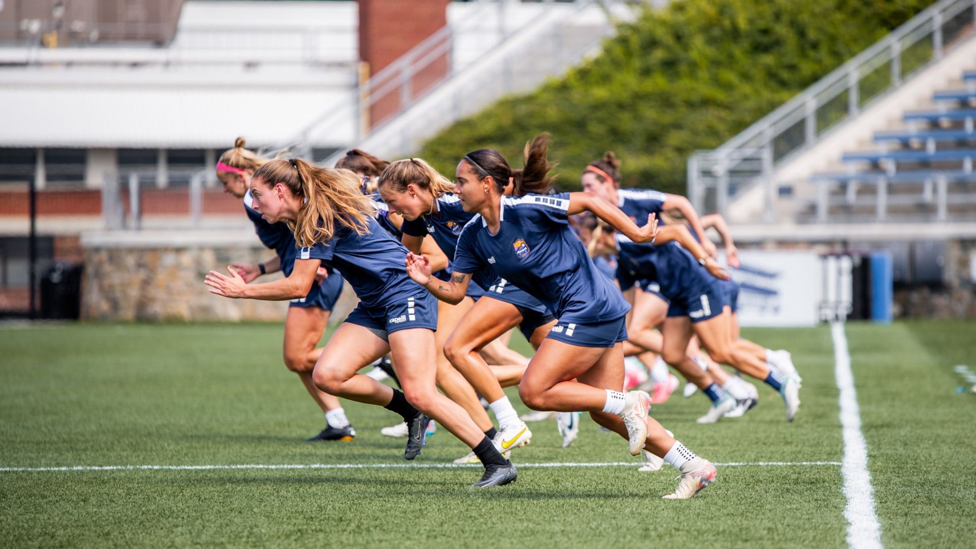 A group of female soccer players running on a field.