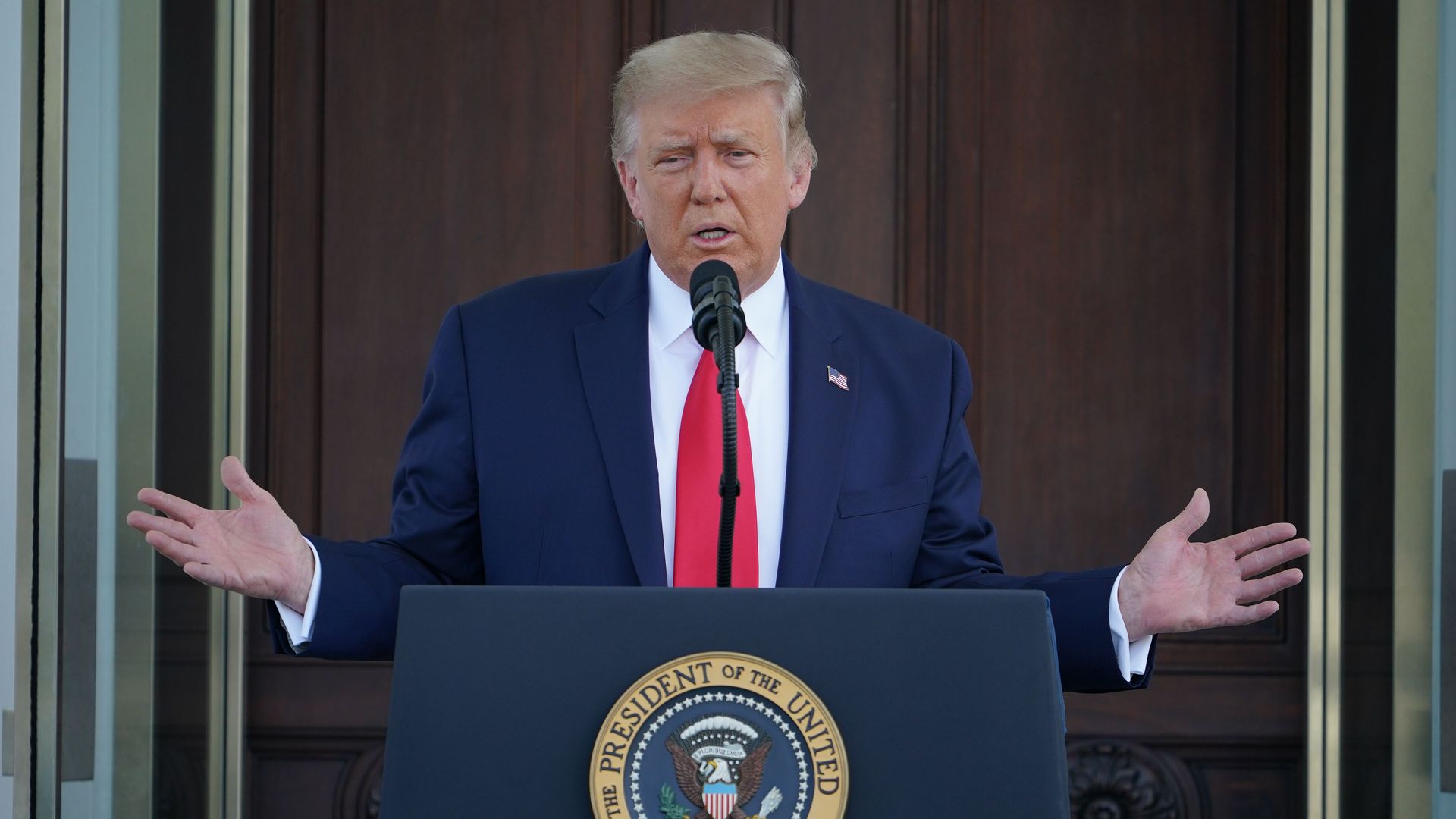 Trump wears a suit at a podium 