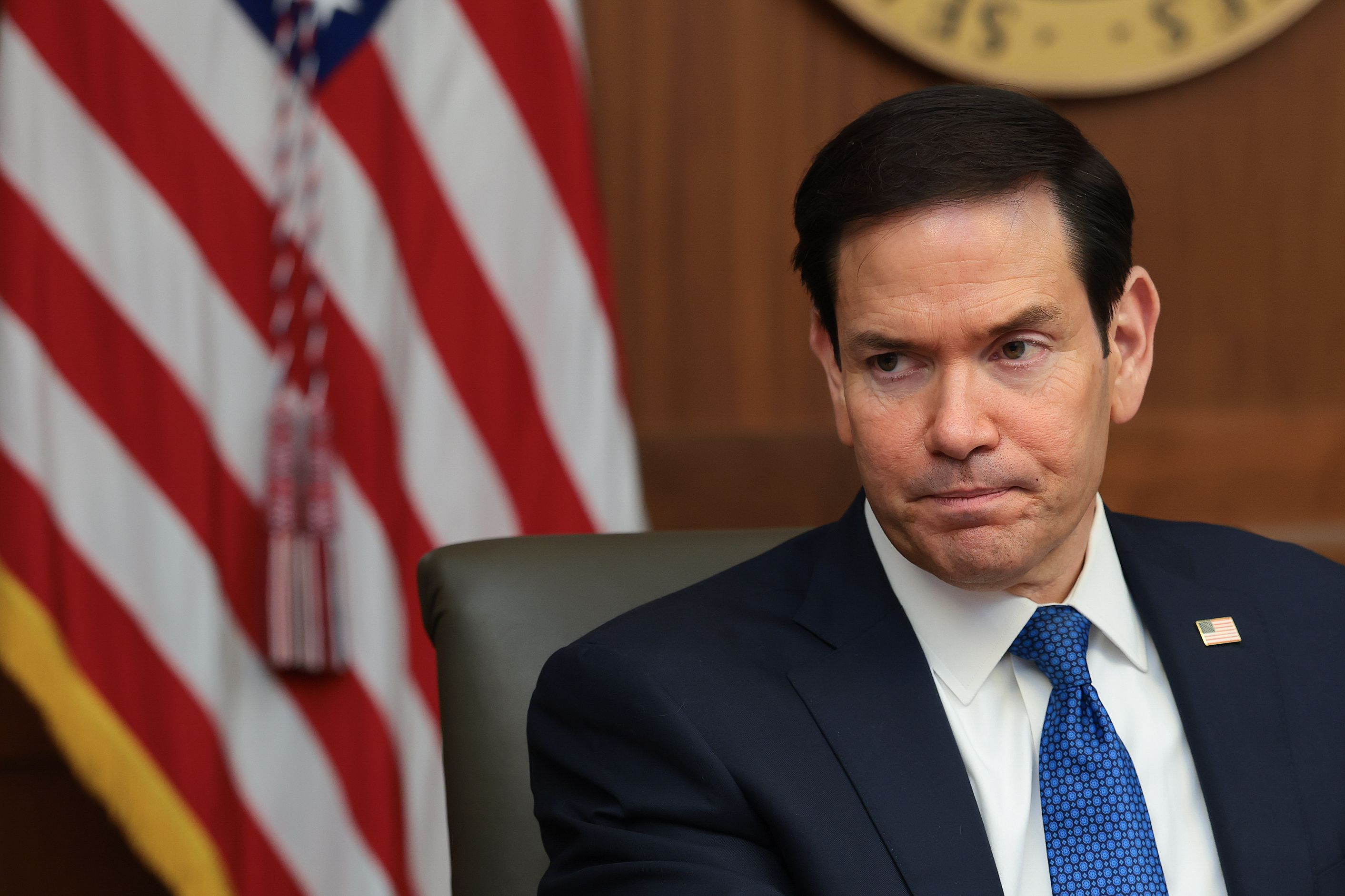 Marco Rubio seated in front of an American flag.