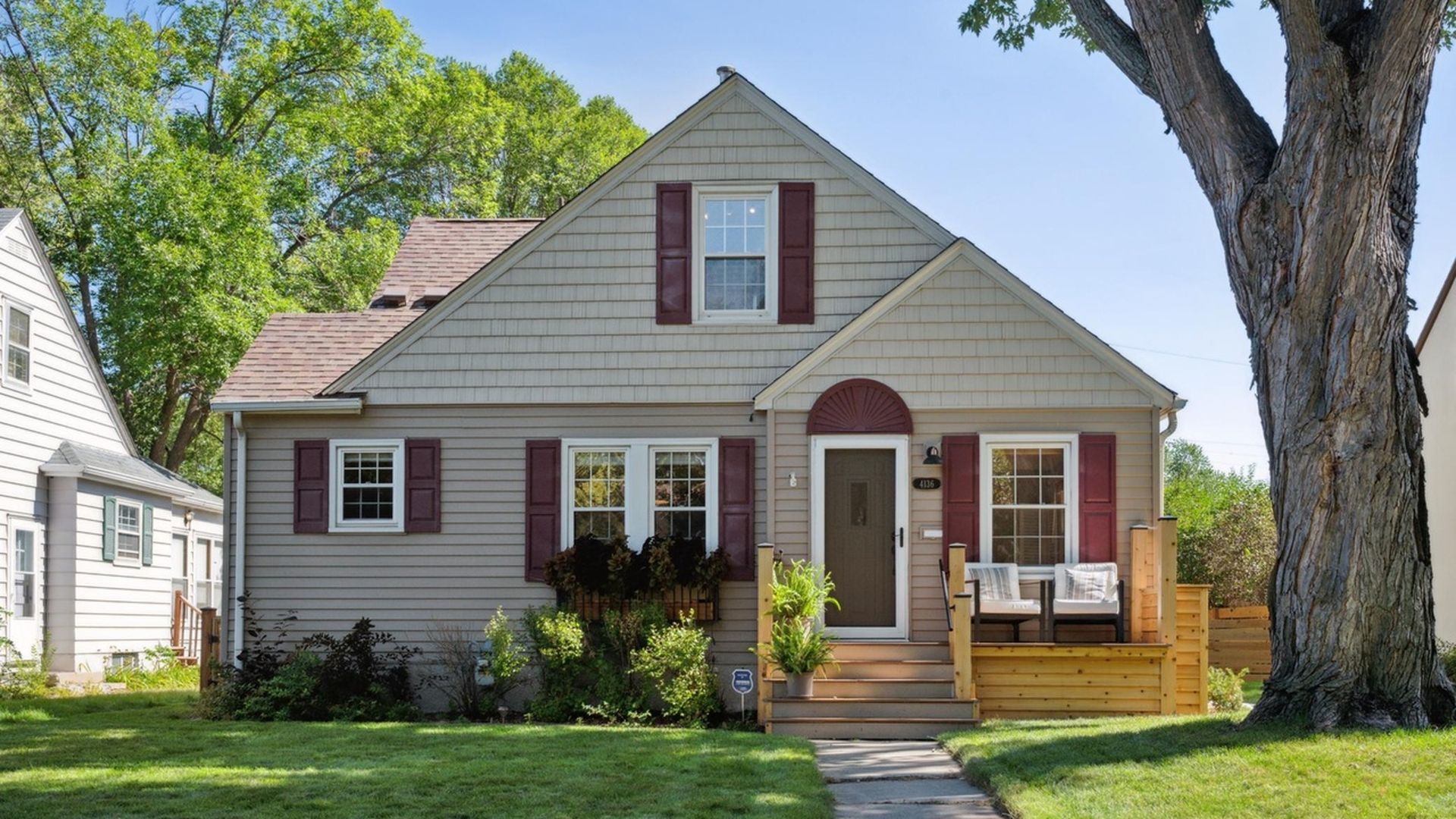 exterior view of beige home with dark accents and large tree in front