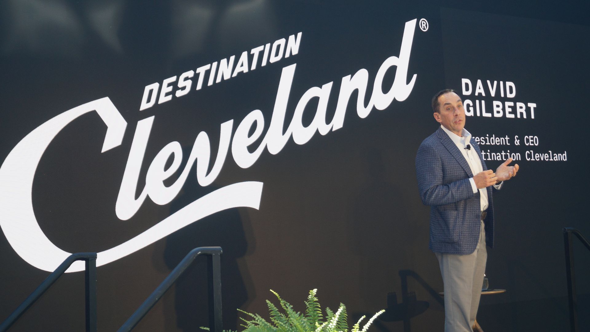 Destination Cleveland CEO David Gilbert speaks on a platform with Destination Cleveland logo in the background