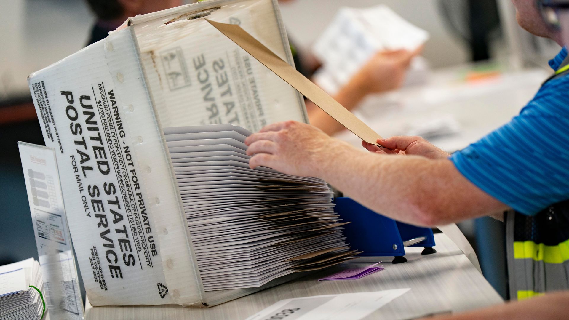 An election worker sorts a stack of mail-in ballot envelopes into a U.S. Postal Service mail tray at the Wake County Board of Elections.