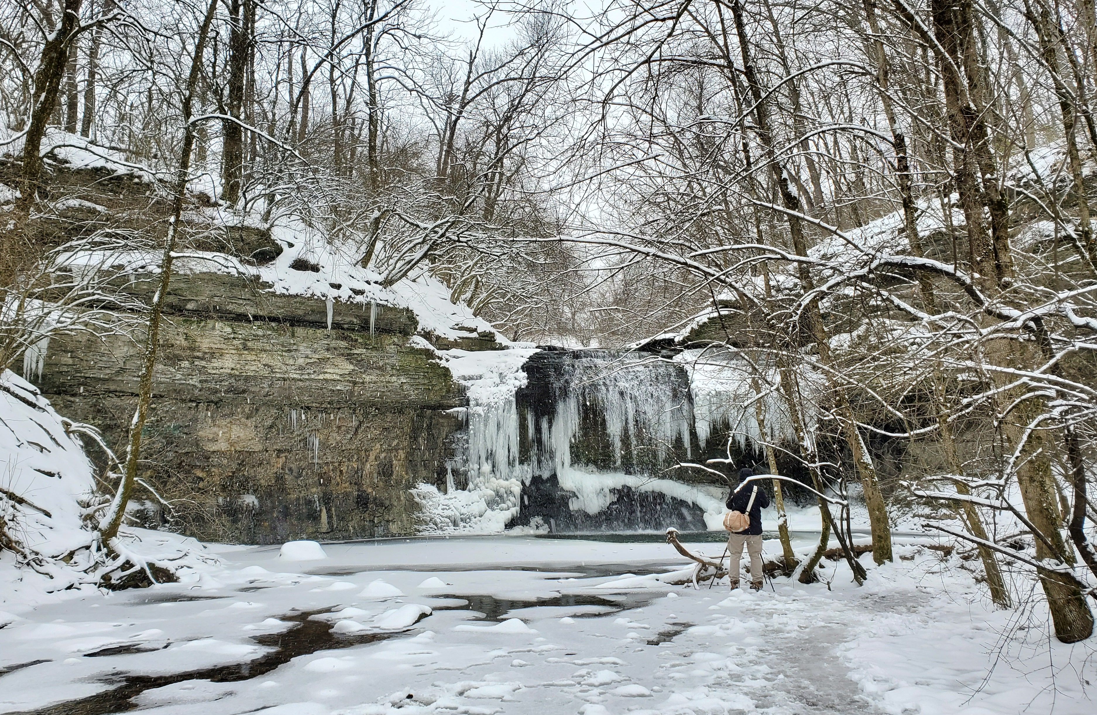 A photographer takes a picture of a frozen waterfall