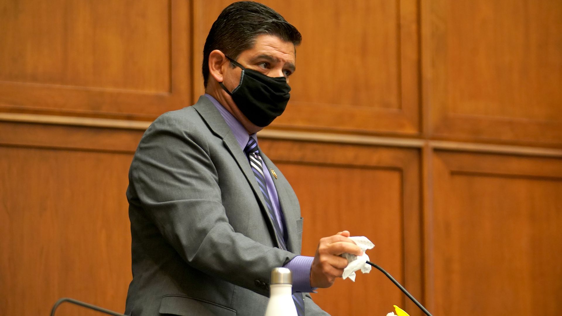 Photo of a masked Raul Ruiz wiping down his microphone at a committee hearing