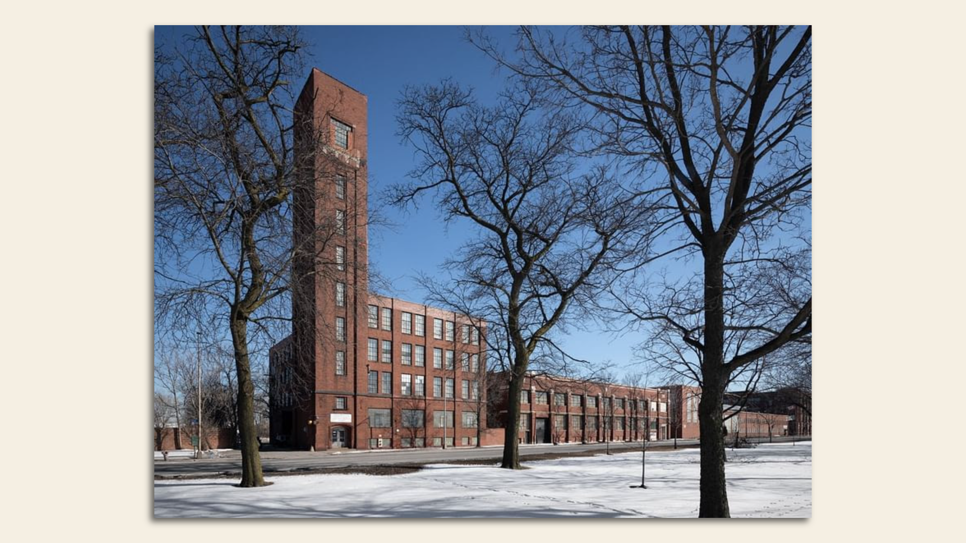 Red brick industrial building with snow on the ground.