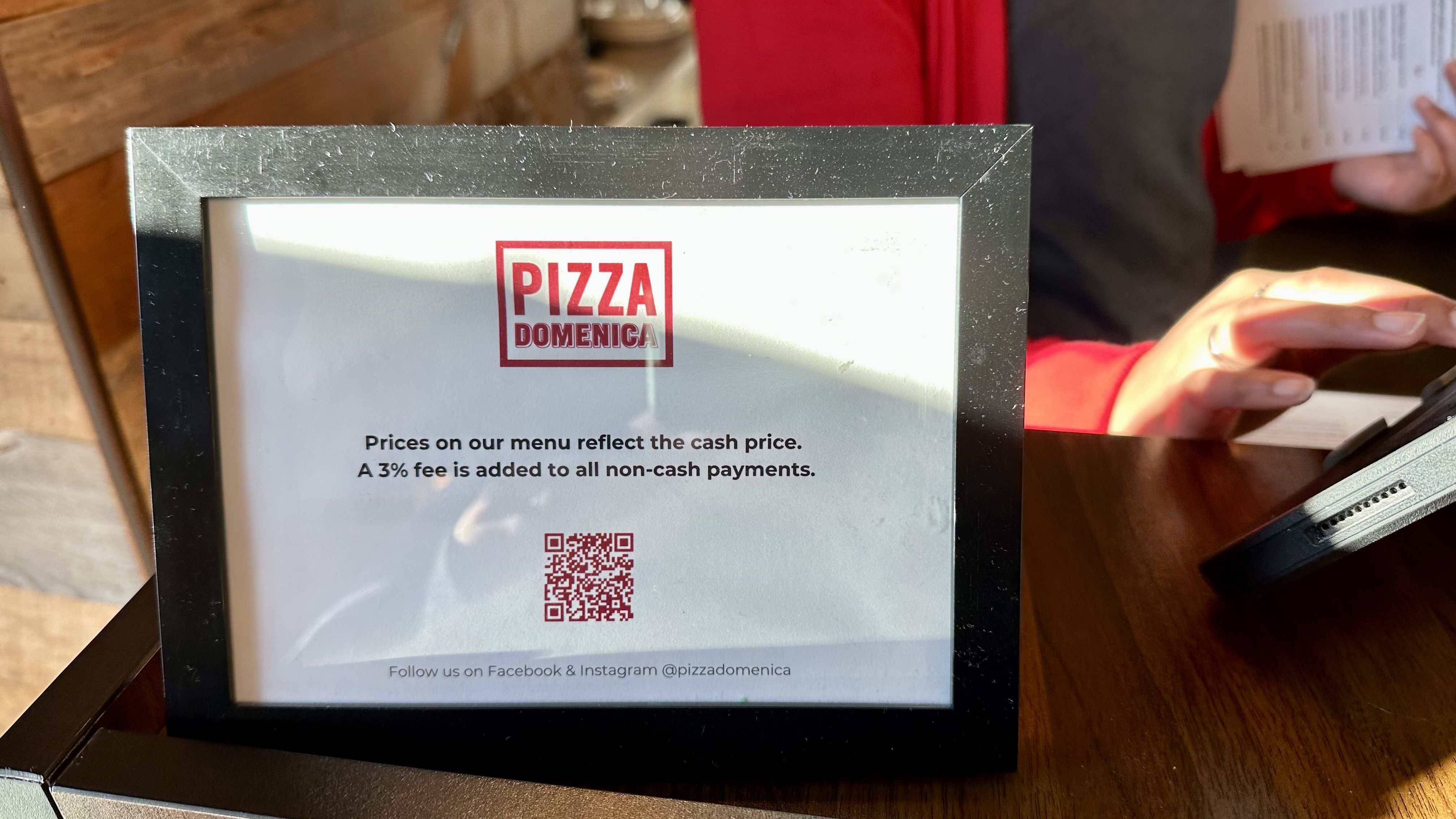 Photo shows a sign at Pizza Domenica saying there's a 3% credit fee.