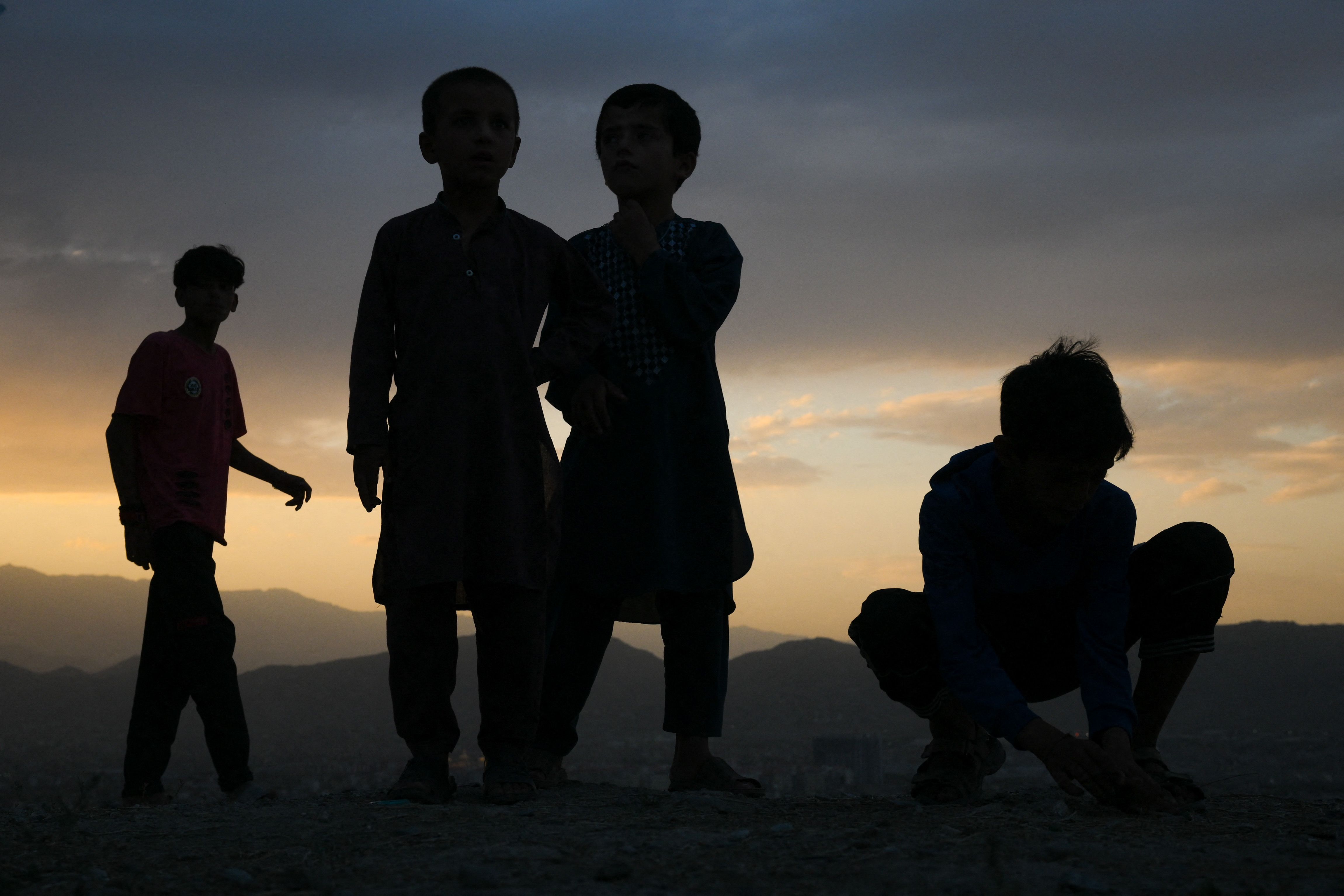 Boys playing marbles at sunset. 