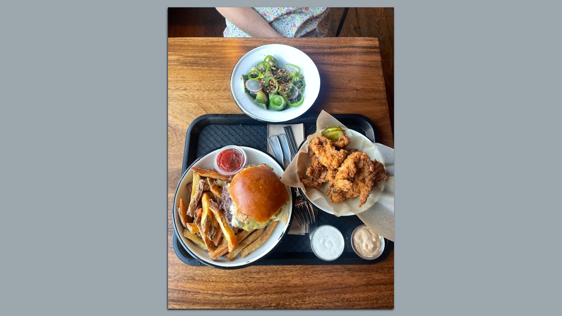 An overhead photo of a meal: burger, chicken tenders, cucumbers