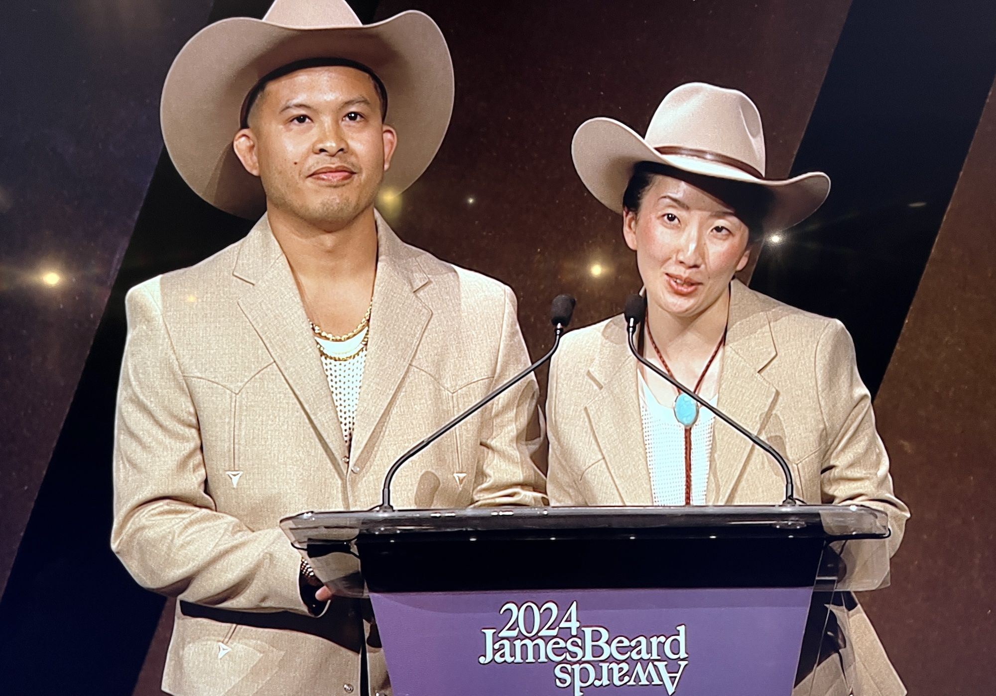 Kasama co-owners in matching khaki suits and cowboy hats.