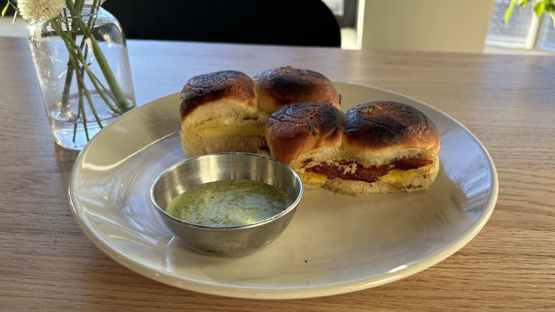 A plate with four buttery rolls sitting on a wooden table.
