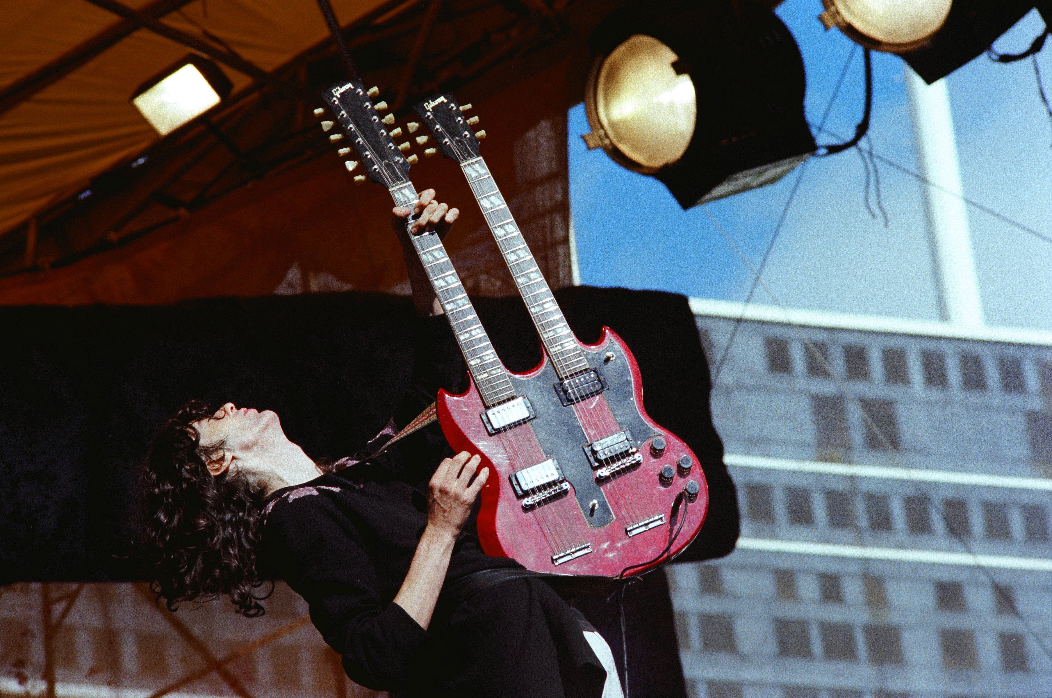 Jimmy Page of Led Zeppelin performs on stage circa 1977 with a black shirt and red double-neck guitar.
