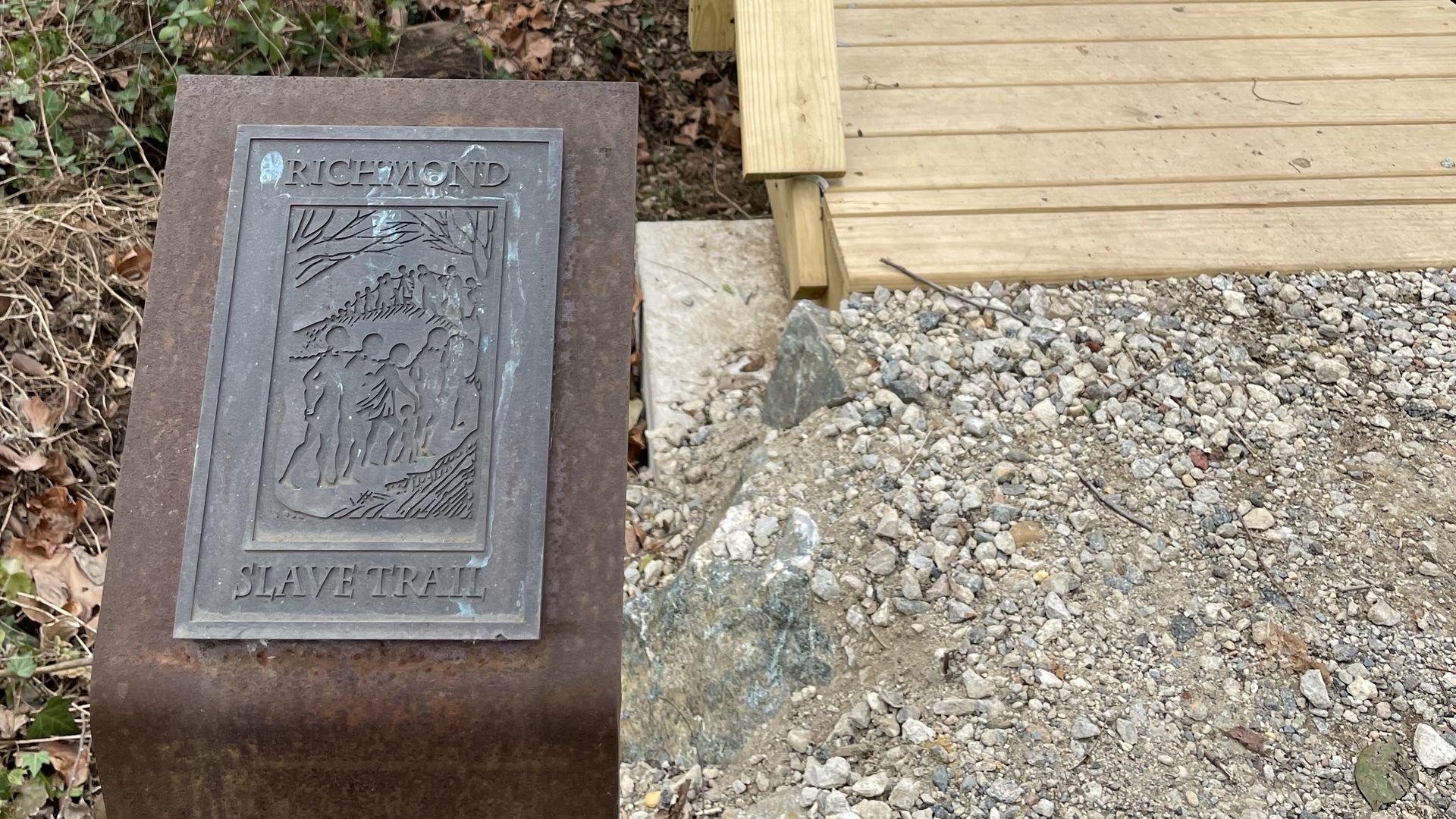 A small wooden bridge next to a sign that says Richmond slave trail 