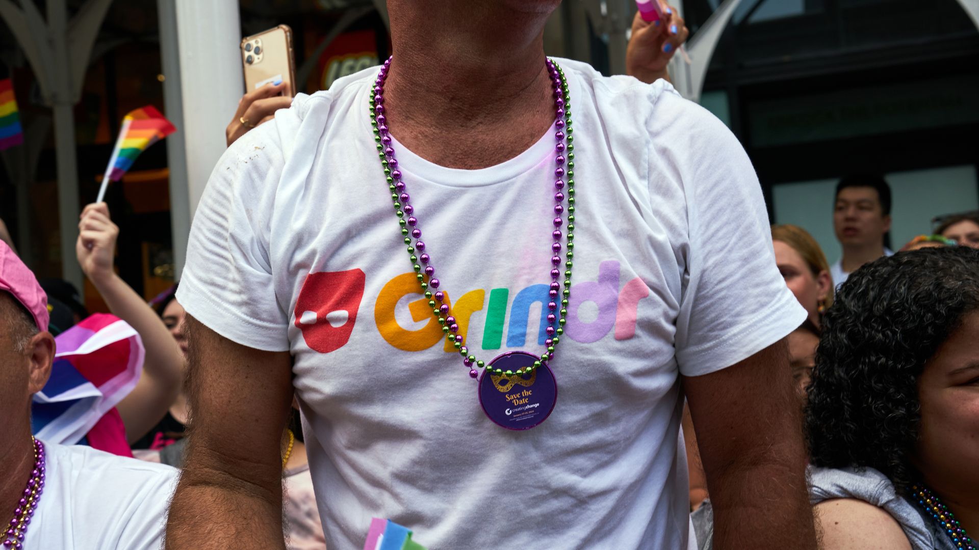 A person wears a shirt reading "Grindr" in rainbow colors. 