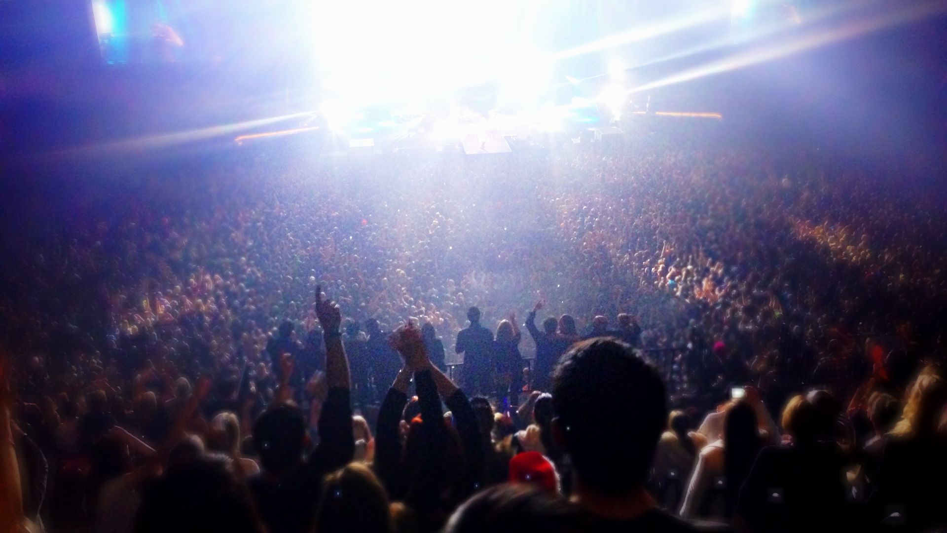 Photo of a crowd cheering in front of a brightly lit stage