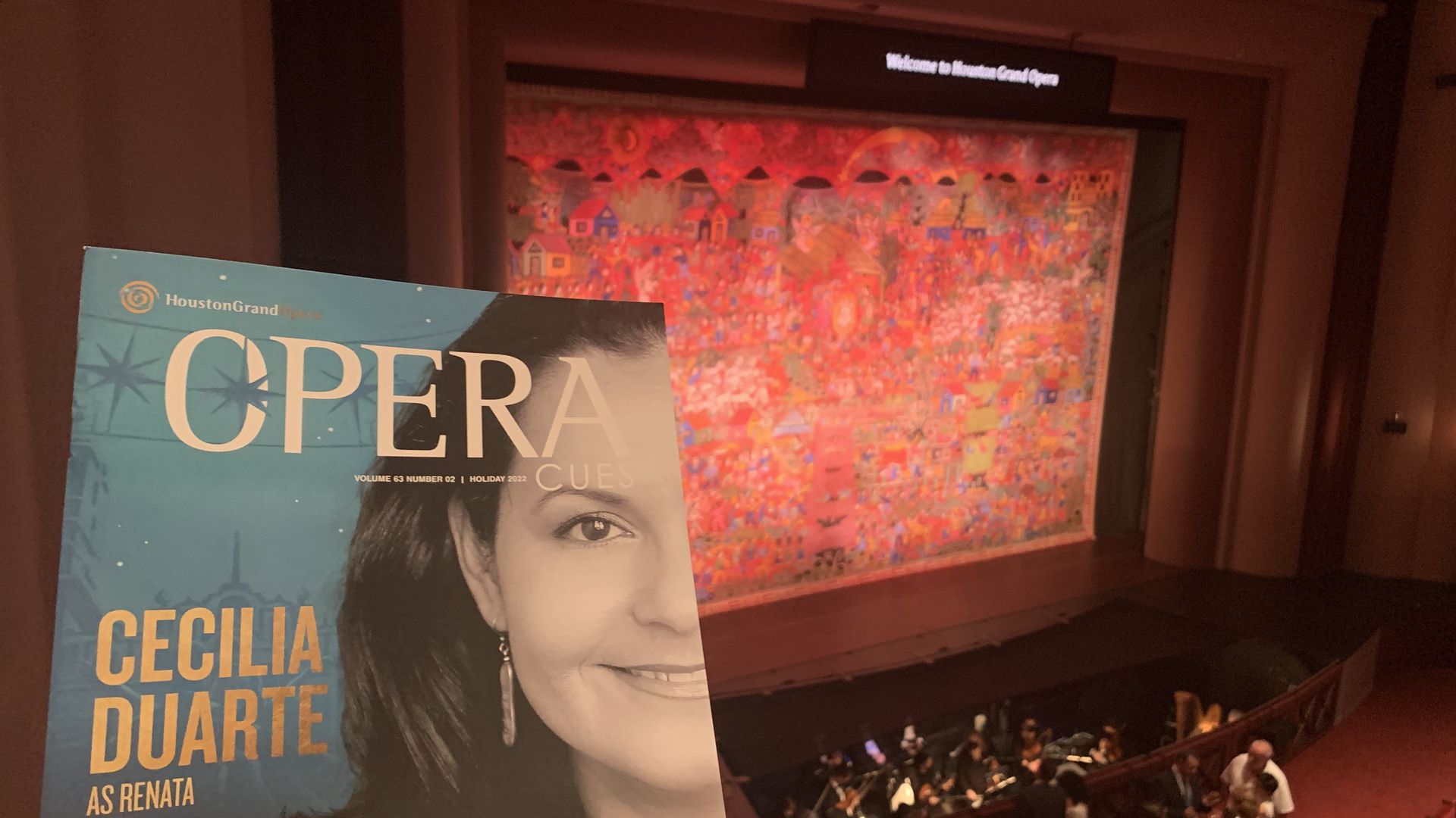 A photo of a blue playbill in front of a stage