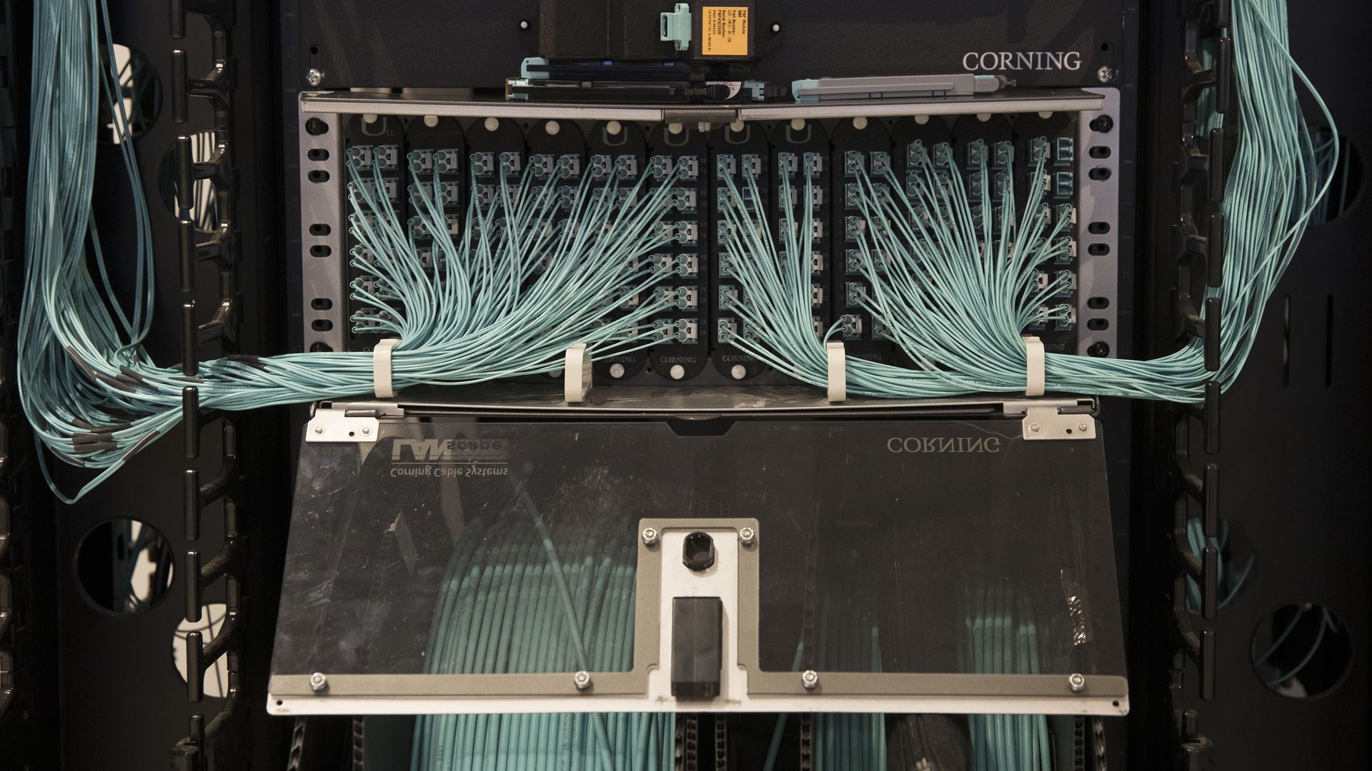 Photo of a box with fiber optic cables plugged into it and the name Corning